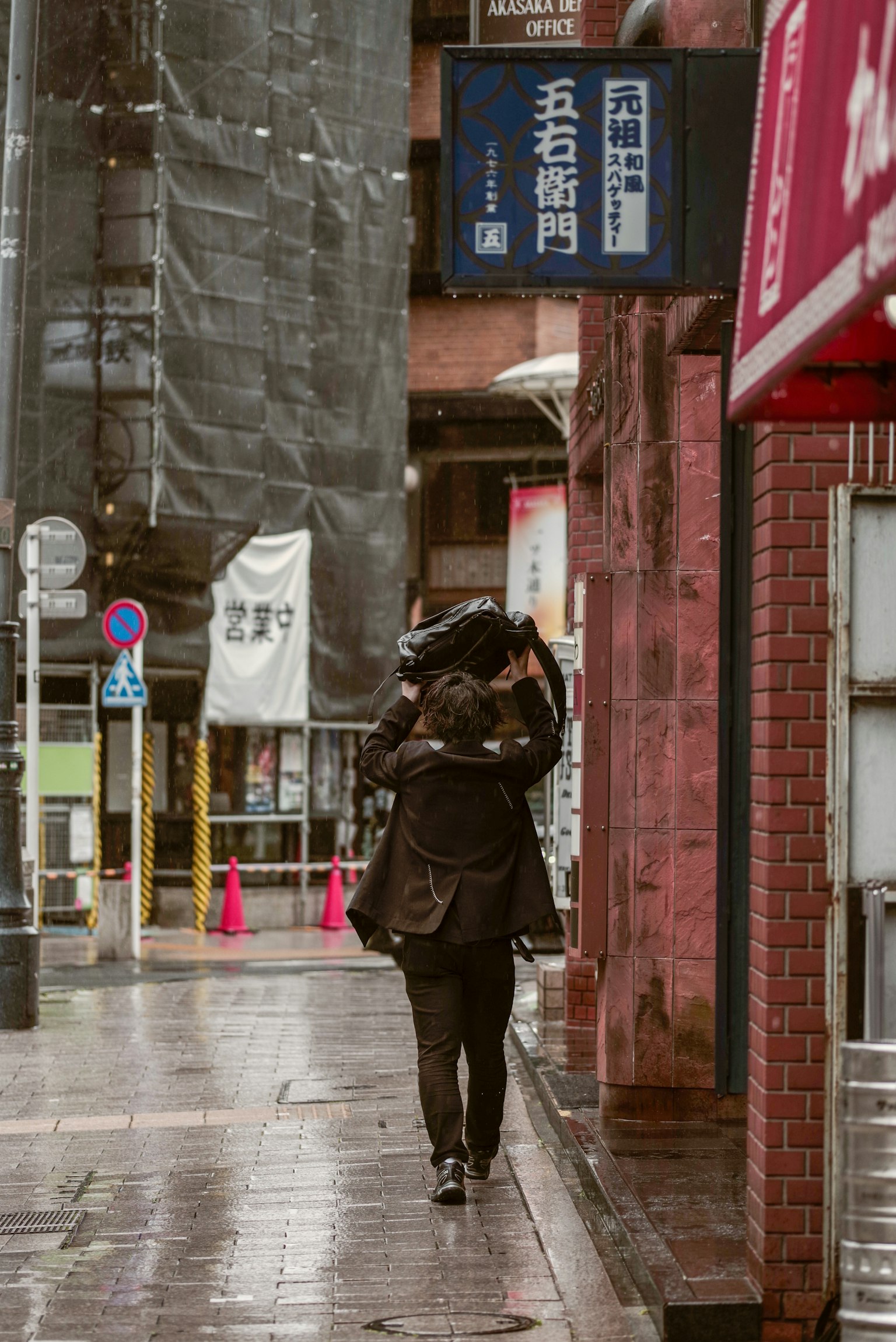 คนเดินในฝนถือกระเป๋าบนหลังในถนนเมือง