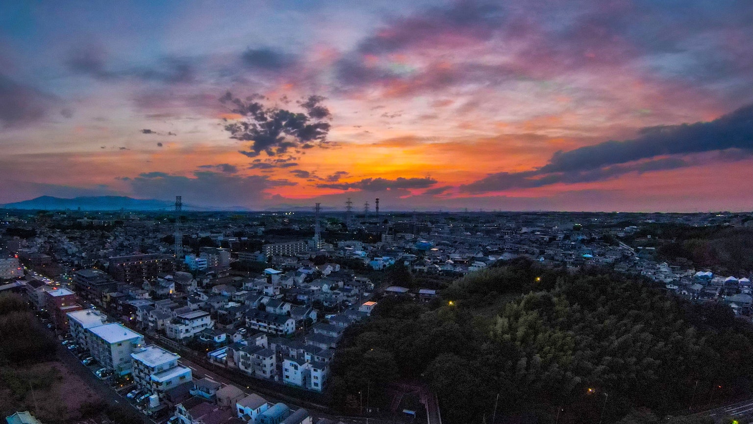 Panoramablick auf eine Stadtlandschaft bei Sonnenuntergang mit bunten Wolken