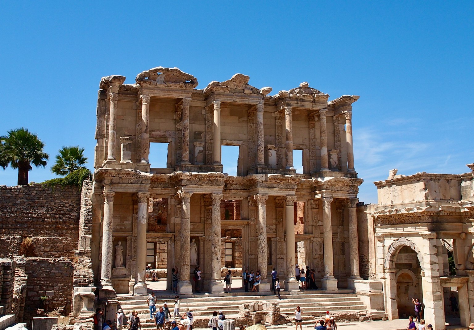 Ruins of the ancient Library of Celsus in Ephesus with tourists under a clear blue sky