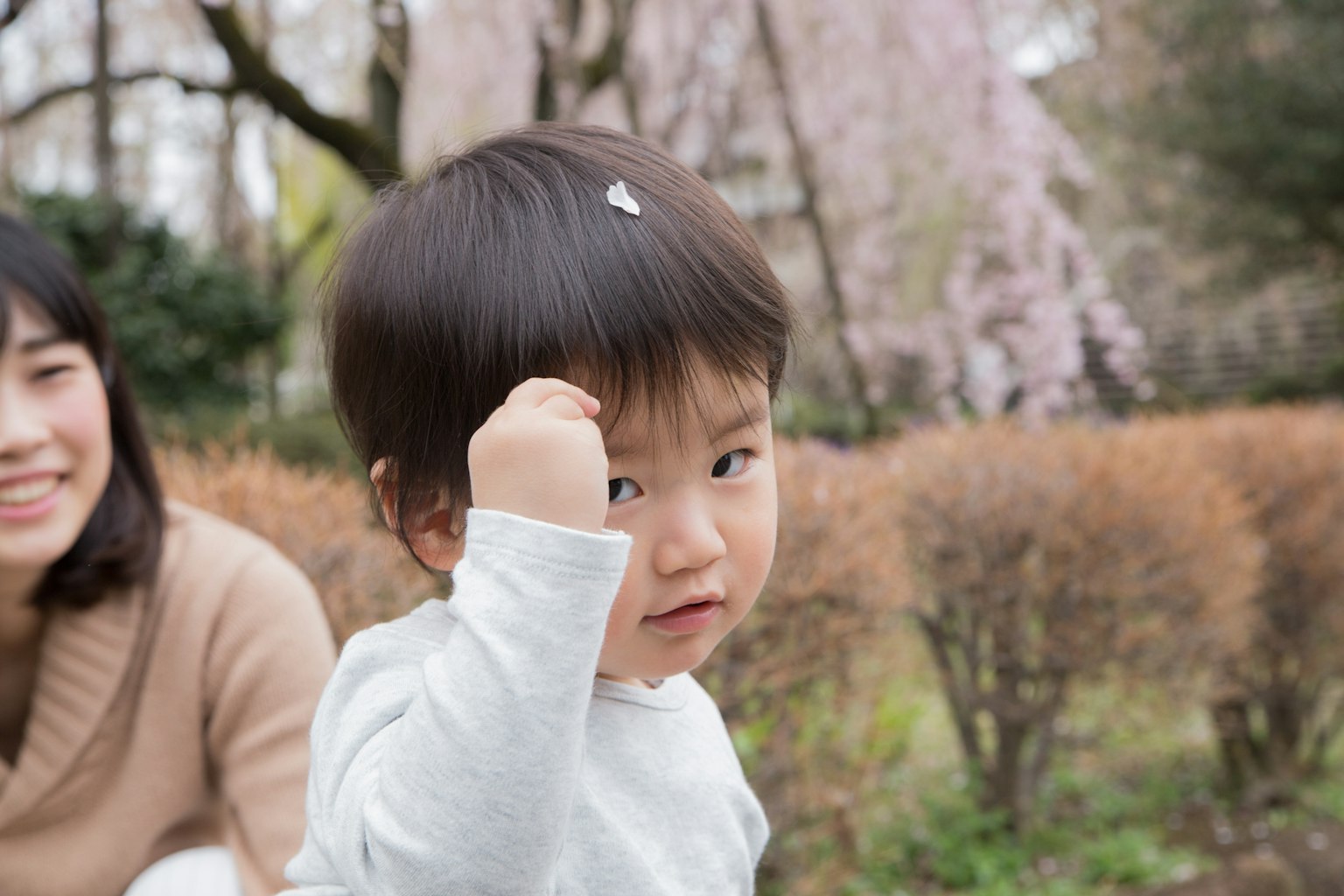 Bambino che gioca in un parco con una madre sorridente sullo sfondo