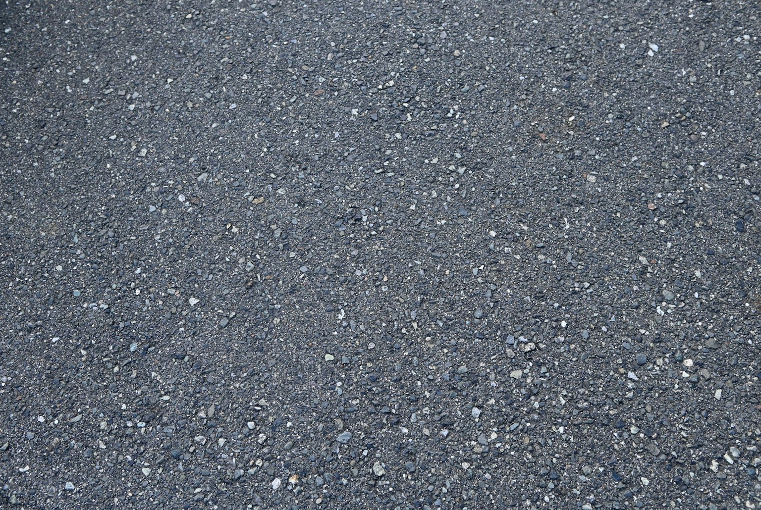 Gray asphalt surface with small white stones scattered throughout