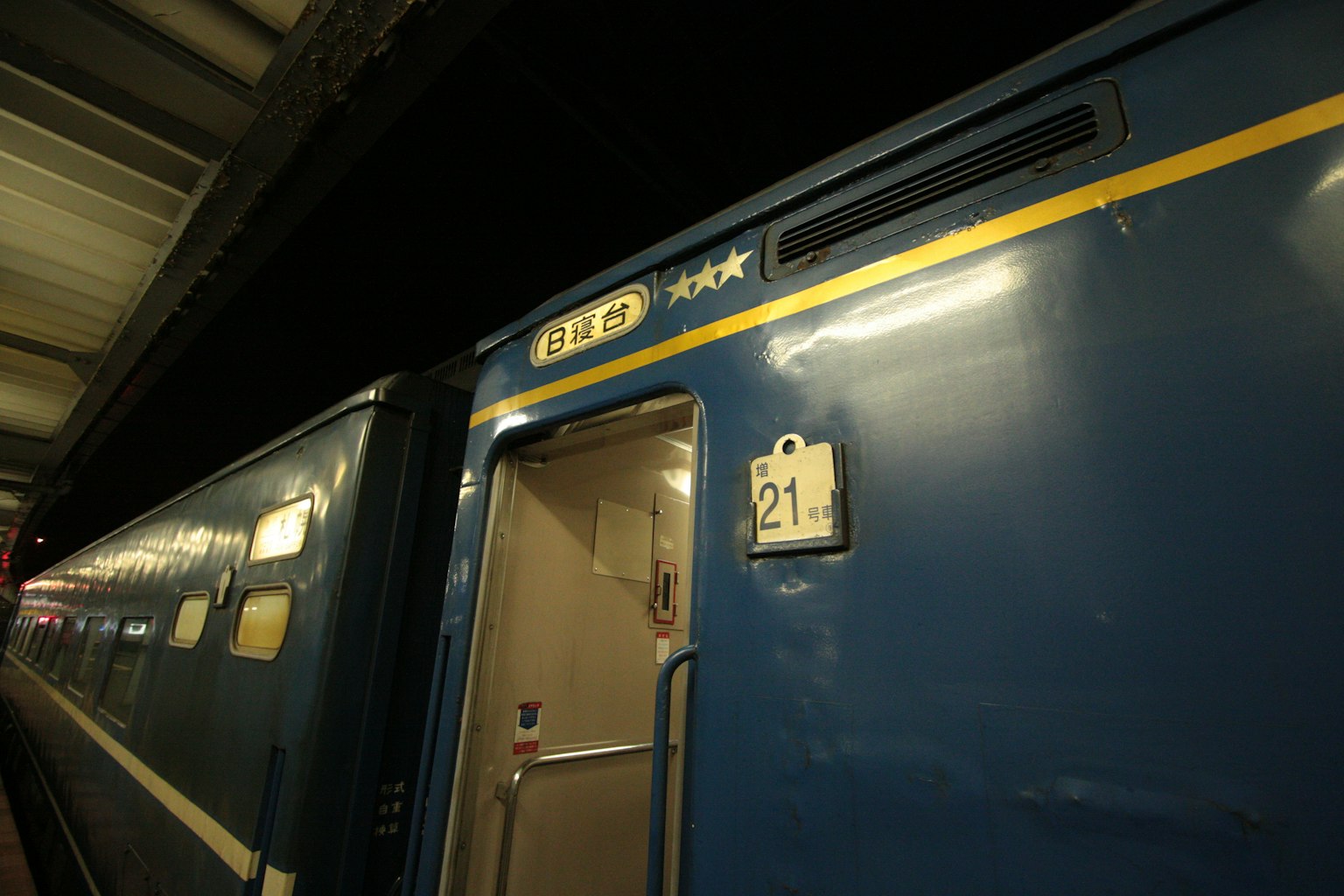 Blue train door with car number 21 visible at a train station platform