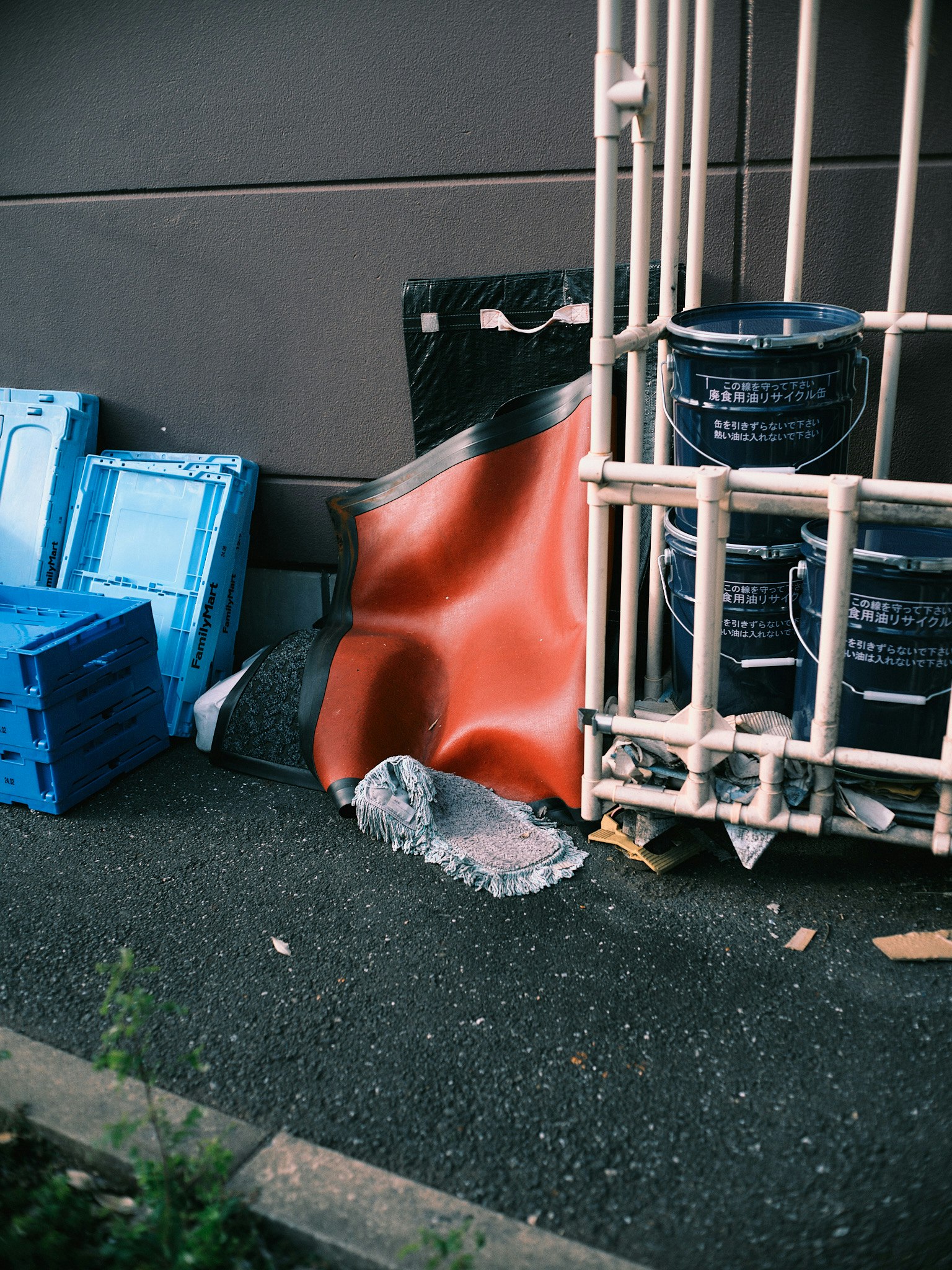 Area dengan keranjang plastik biru dan lembaran merah dekat sampah