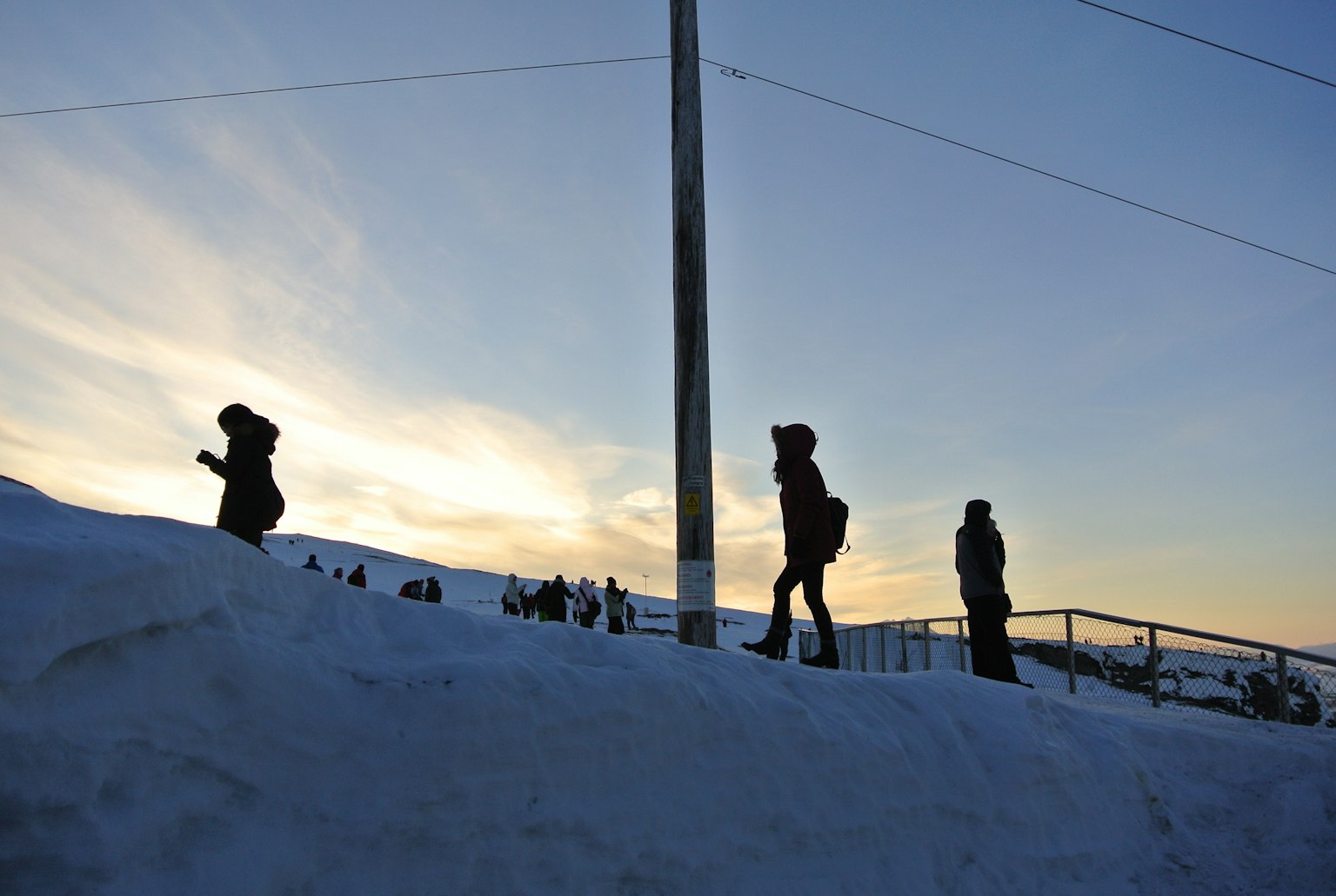 Silhouettes de personnes marchant dans la neige au coucher du soleil