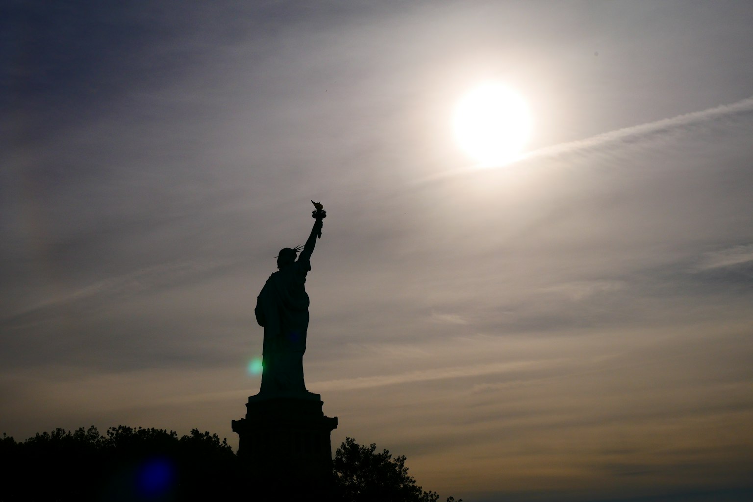 Silhouette della Statua della Libertà contro un sole luminoso
