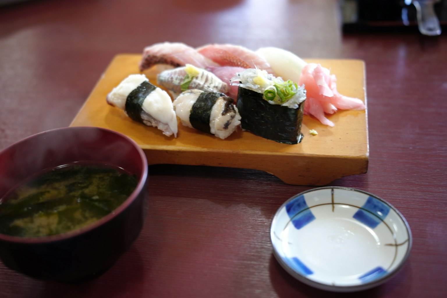 Immagine di sushi servito su un piatto di legno con zuppa di miso