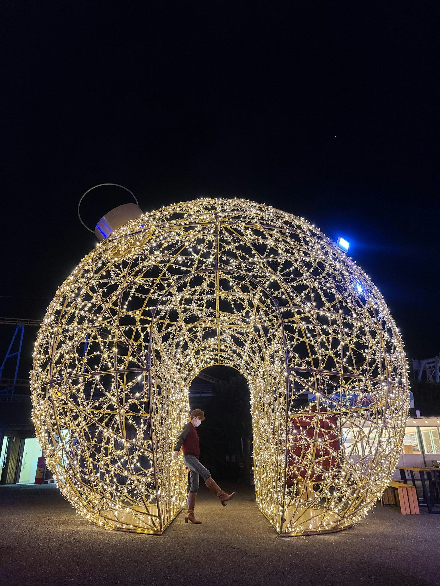 Struttura ad arco decorativa illuminata con luci di notte con una persona davanti