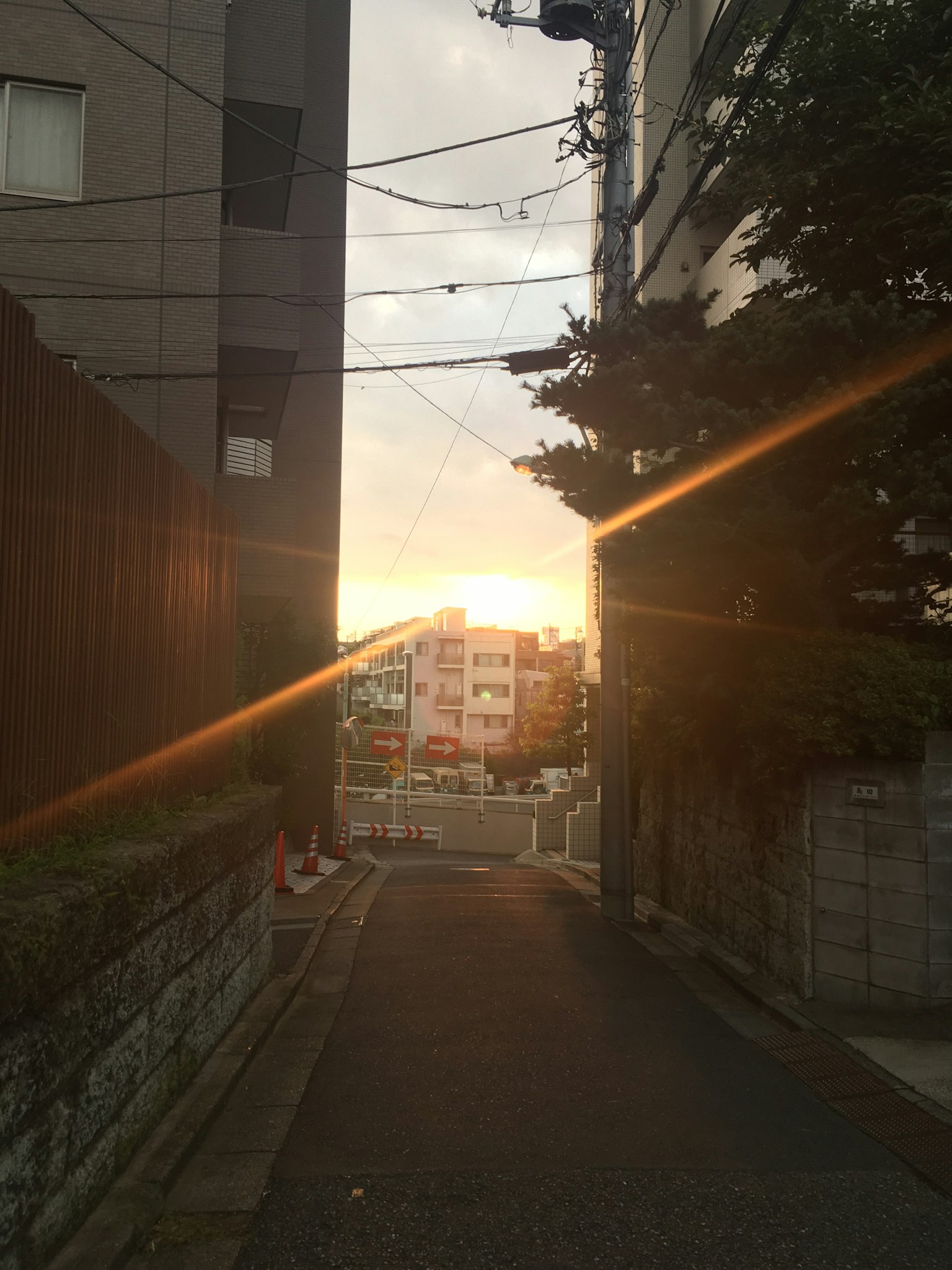Schmale Gasse mit Sonnenuntergangslicht, das Gebäude und Stromleitungen beleuchtet