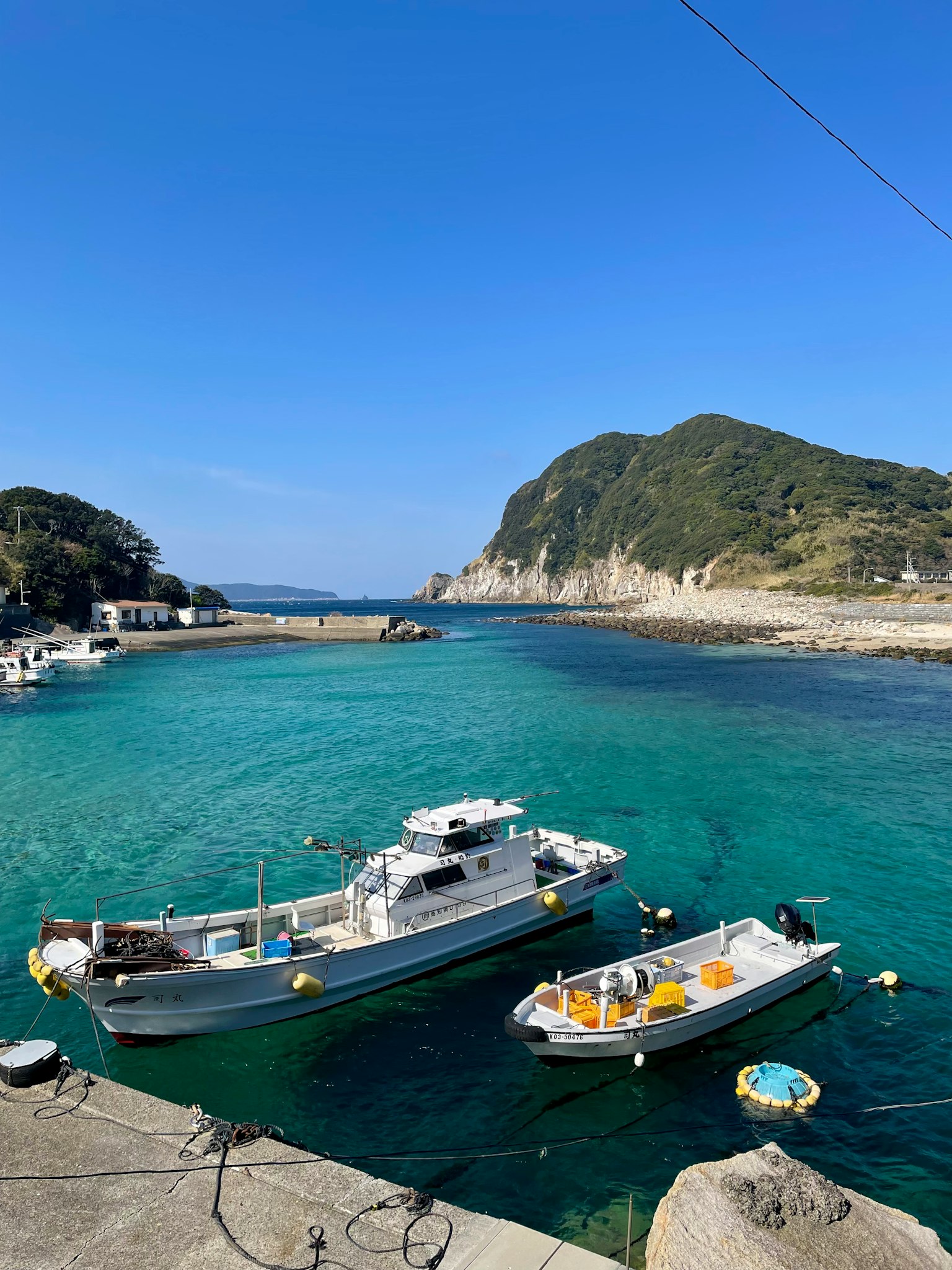 漂浮在蓝色水域中的渔船与风景如画的山脉背景