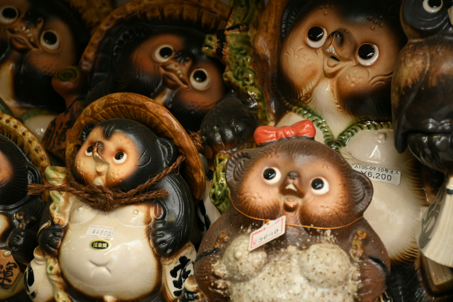 Una colección de figuritas de cerámica de tanuki con diversas expresiones y accesorios
