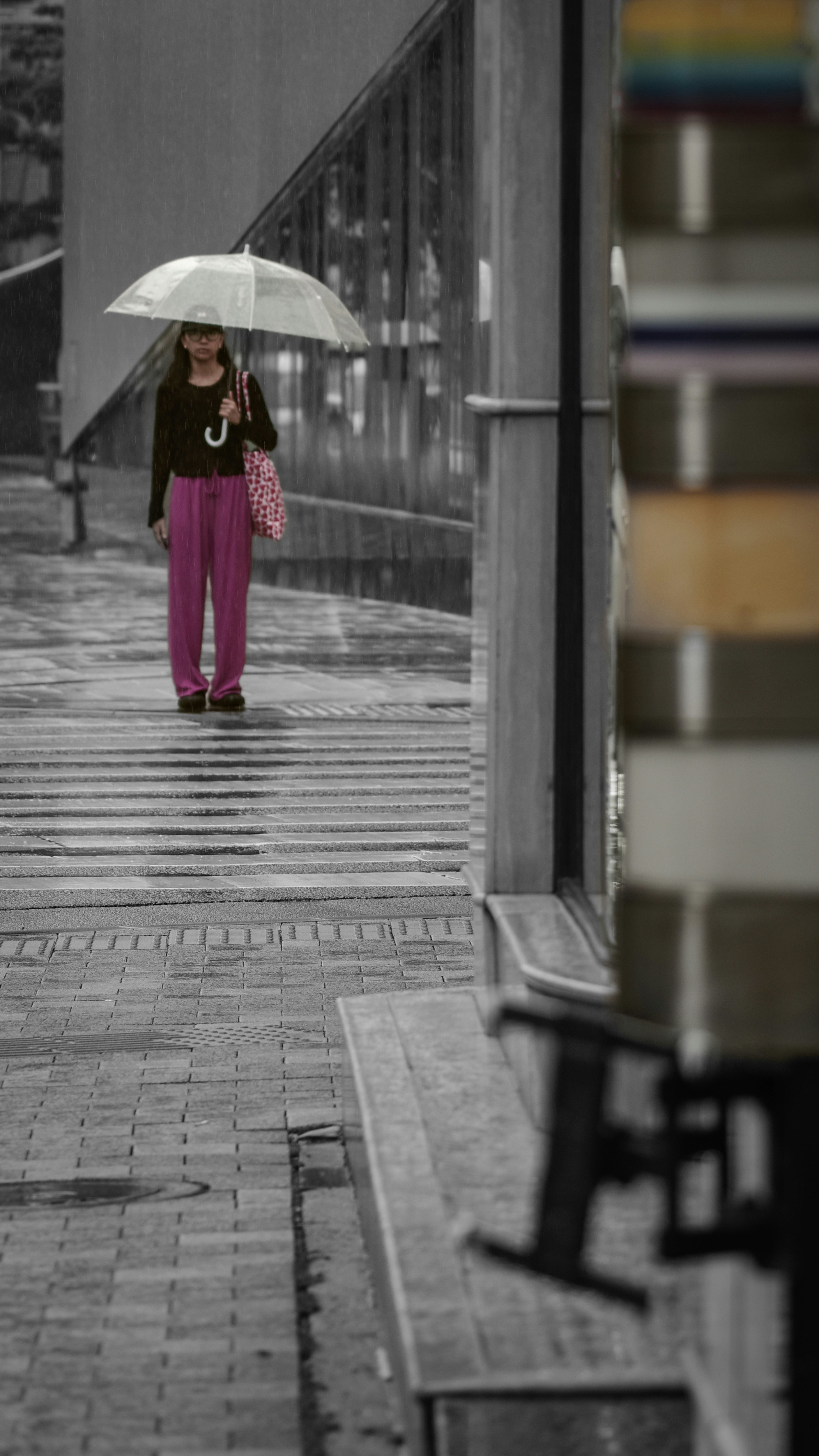 Una persona con paraguas bajo la lluvia en un callejón comercial