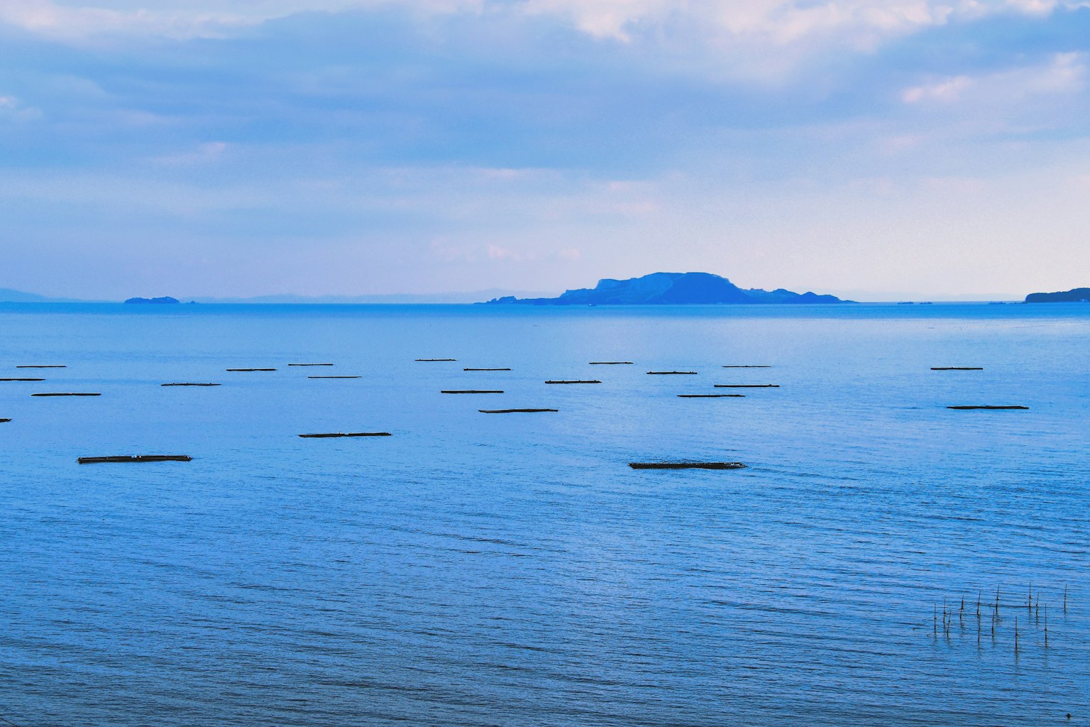 Blaues Meer mit fernen Inseln und bewölktem Himmel