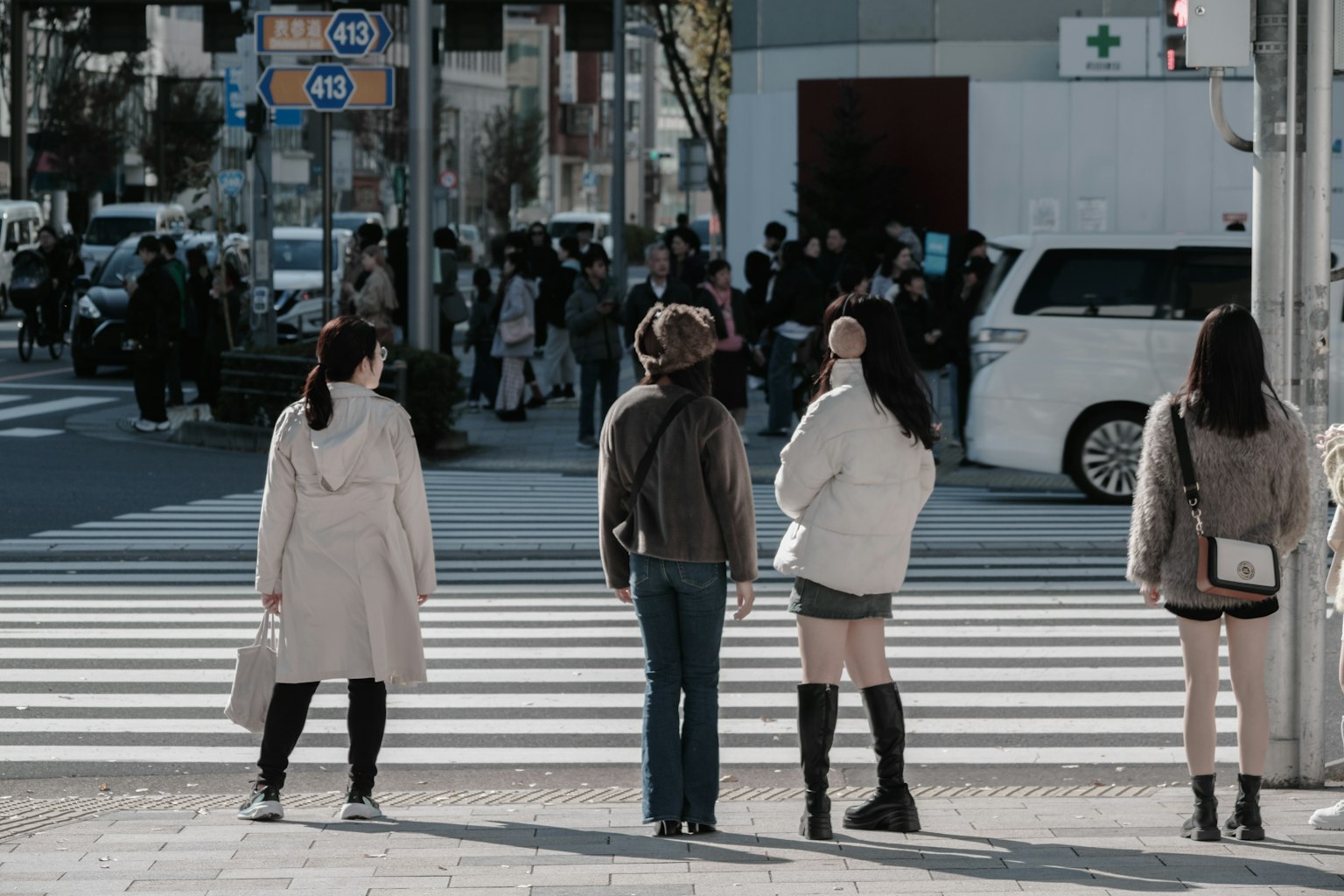 People waiting at a crosswalk city scene with various dressed women