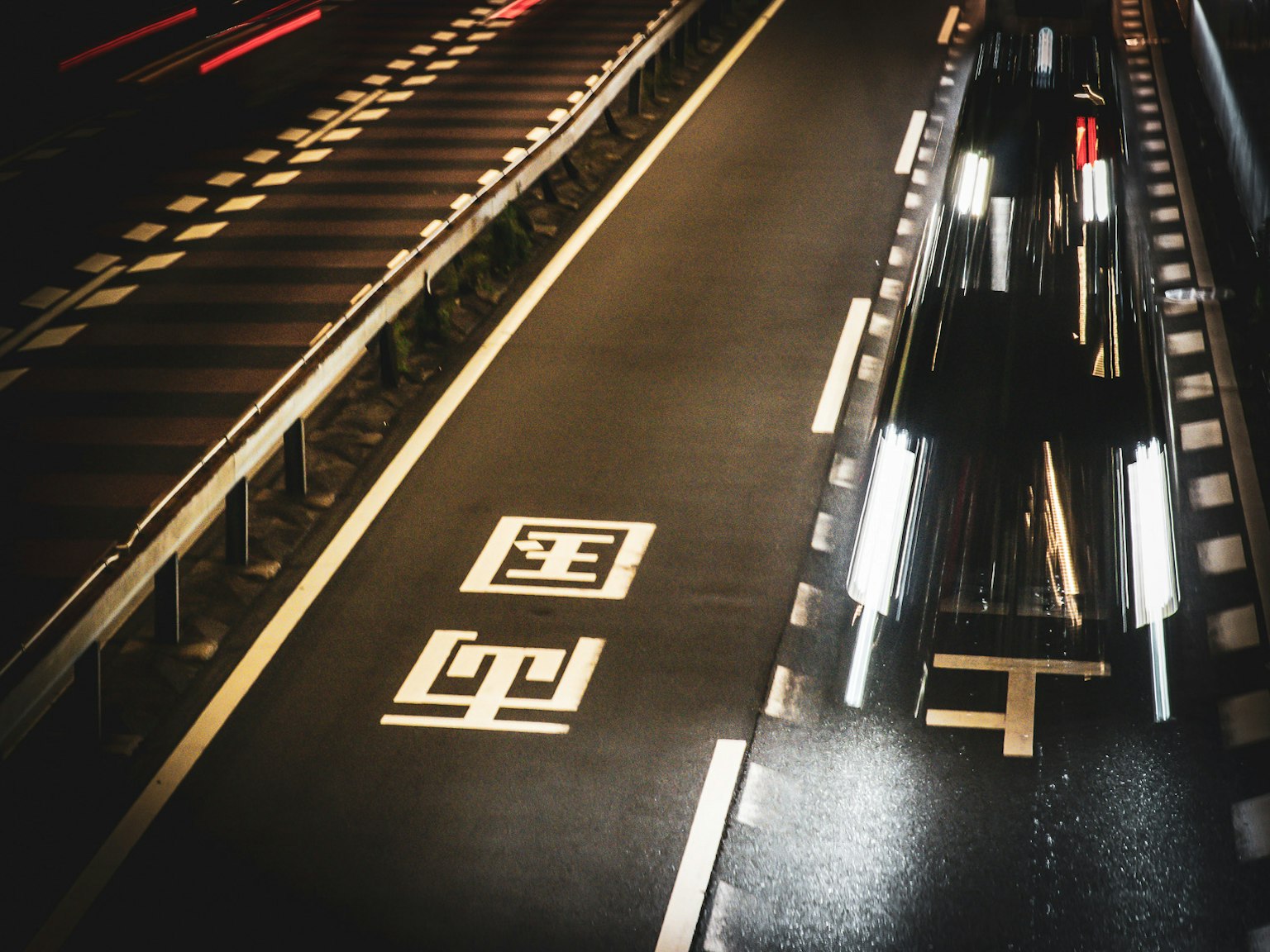 夜の道路に映る車の光と白い交通標識