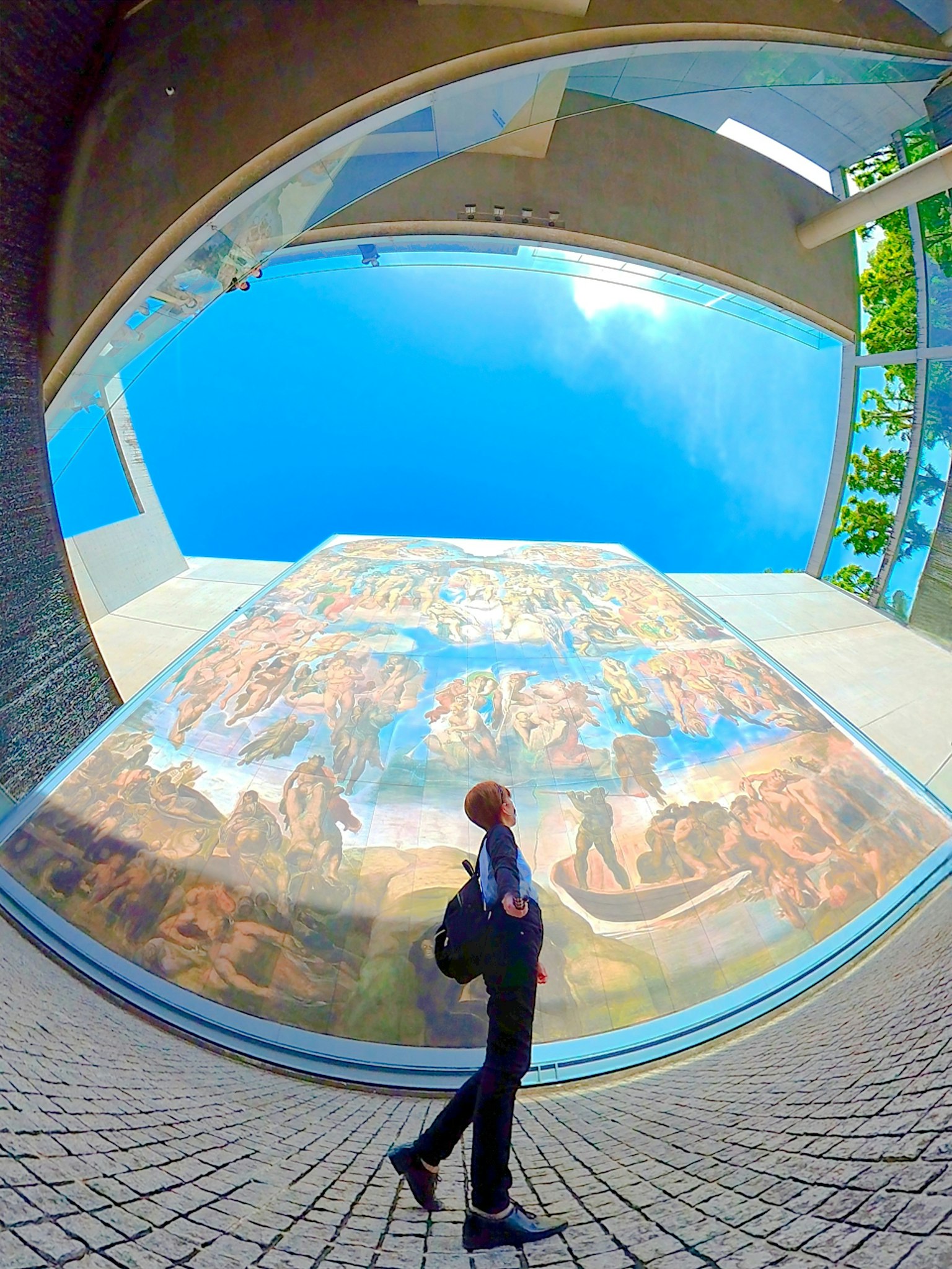 Seseorang mengamati mural di bawah langit biru
