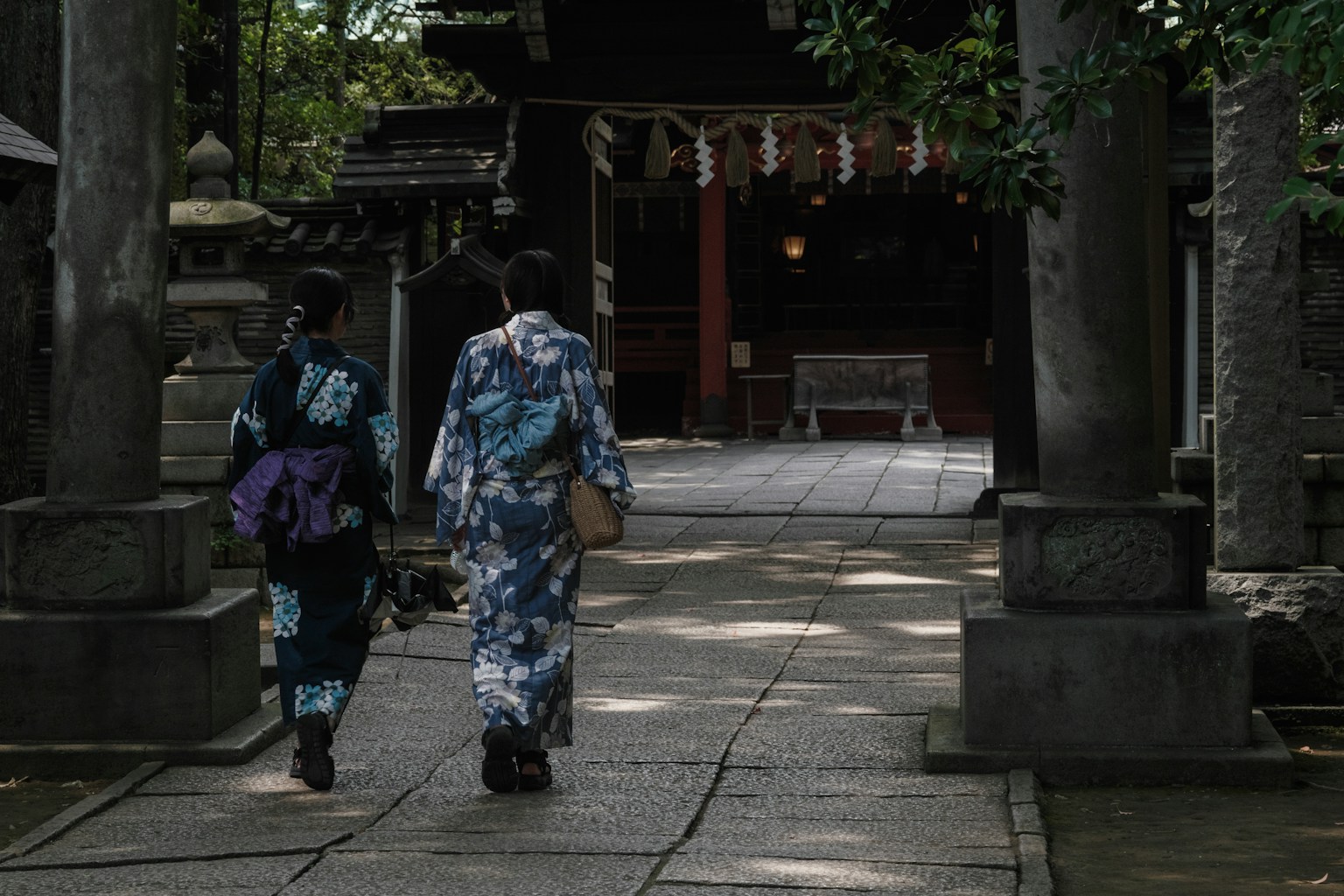 Two women in kimono walking along a path at a shrine