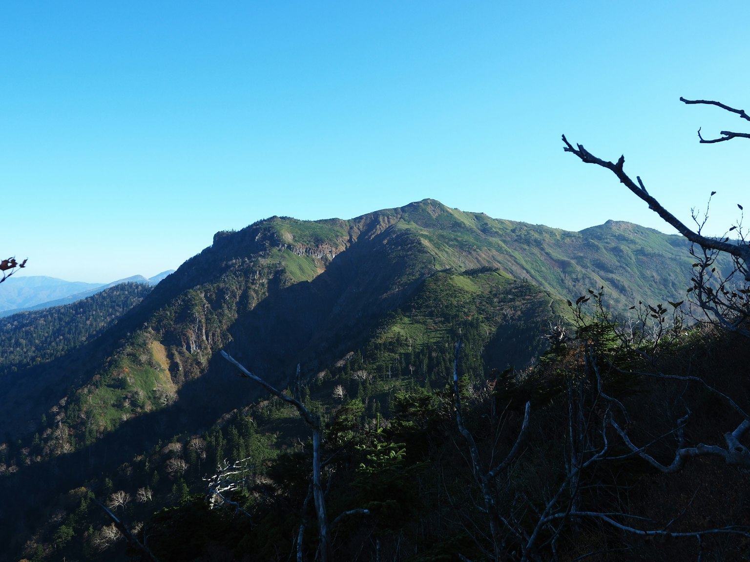 Gunung hijau subur di bawah langit biru yang cerah