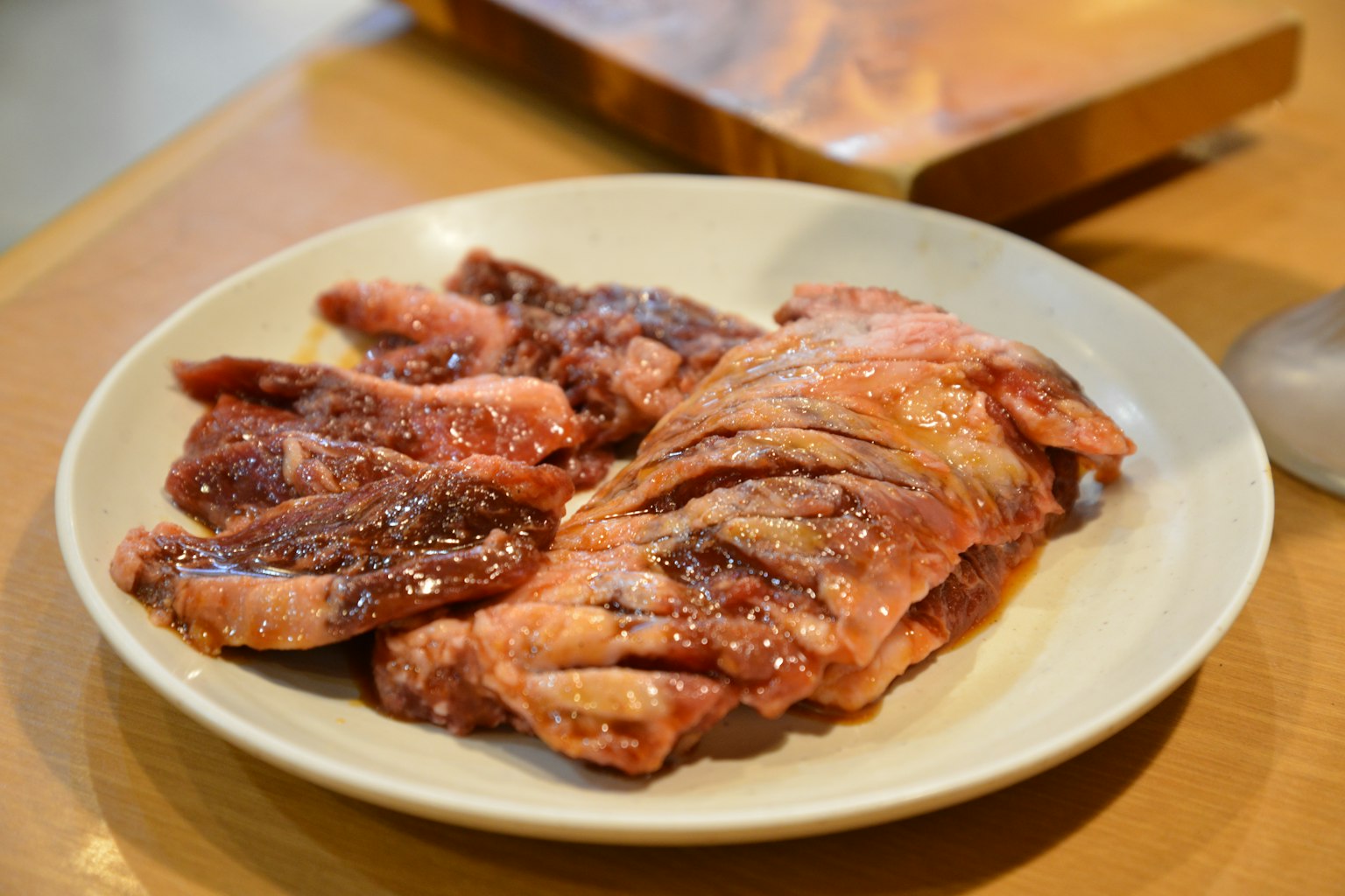 Un piatto di carne marinata per grigliare con tonalità rosse e marroni vivaci un tagliere di legno sullo sfondo