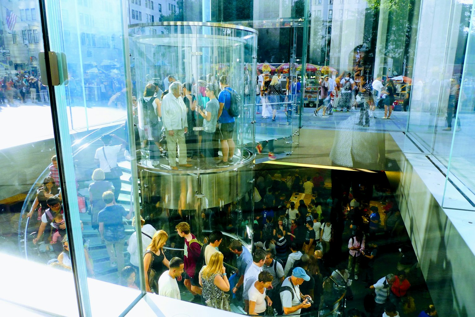Folla di persone all'interno di un edificio di vetro con un ascensore circolare