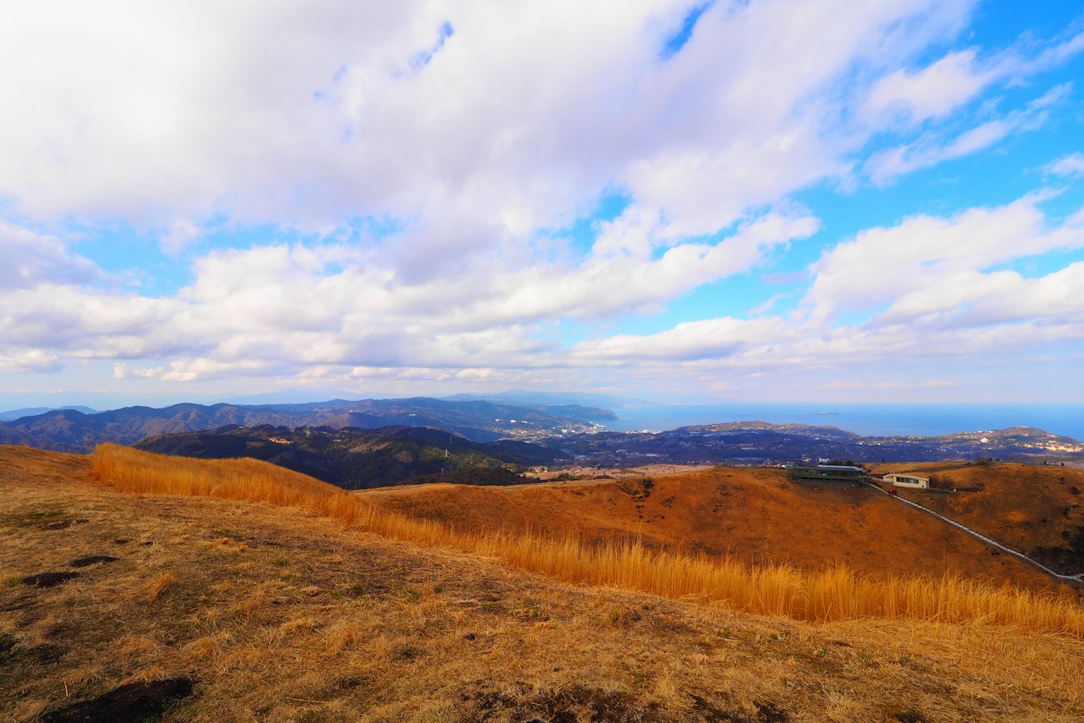 Pemandangan gunung dengan langit biru dan awan putih Padang rumput kering dan bukit jauh