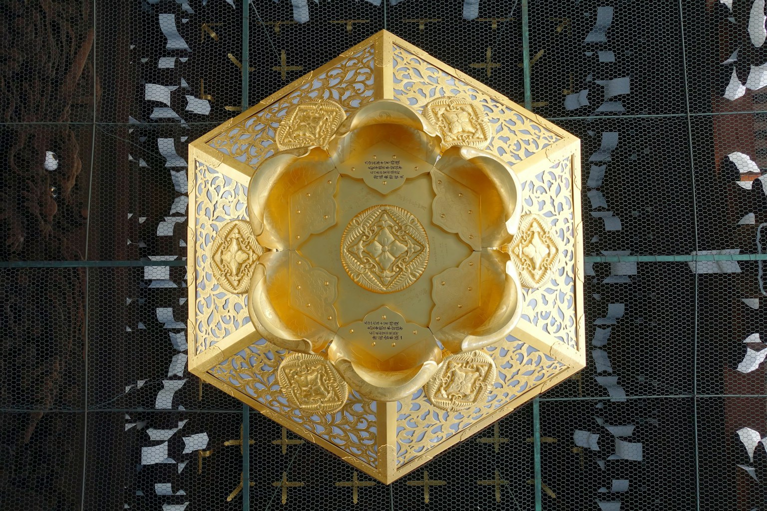 金色六角装饰盘的顶部视图，具有复杂的图案和光泽