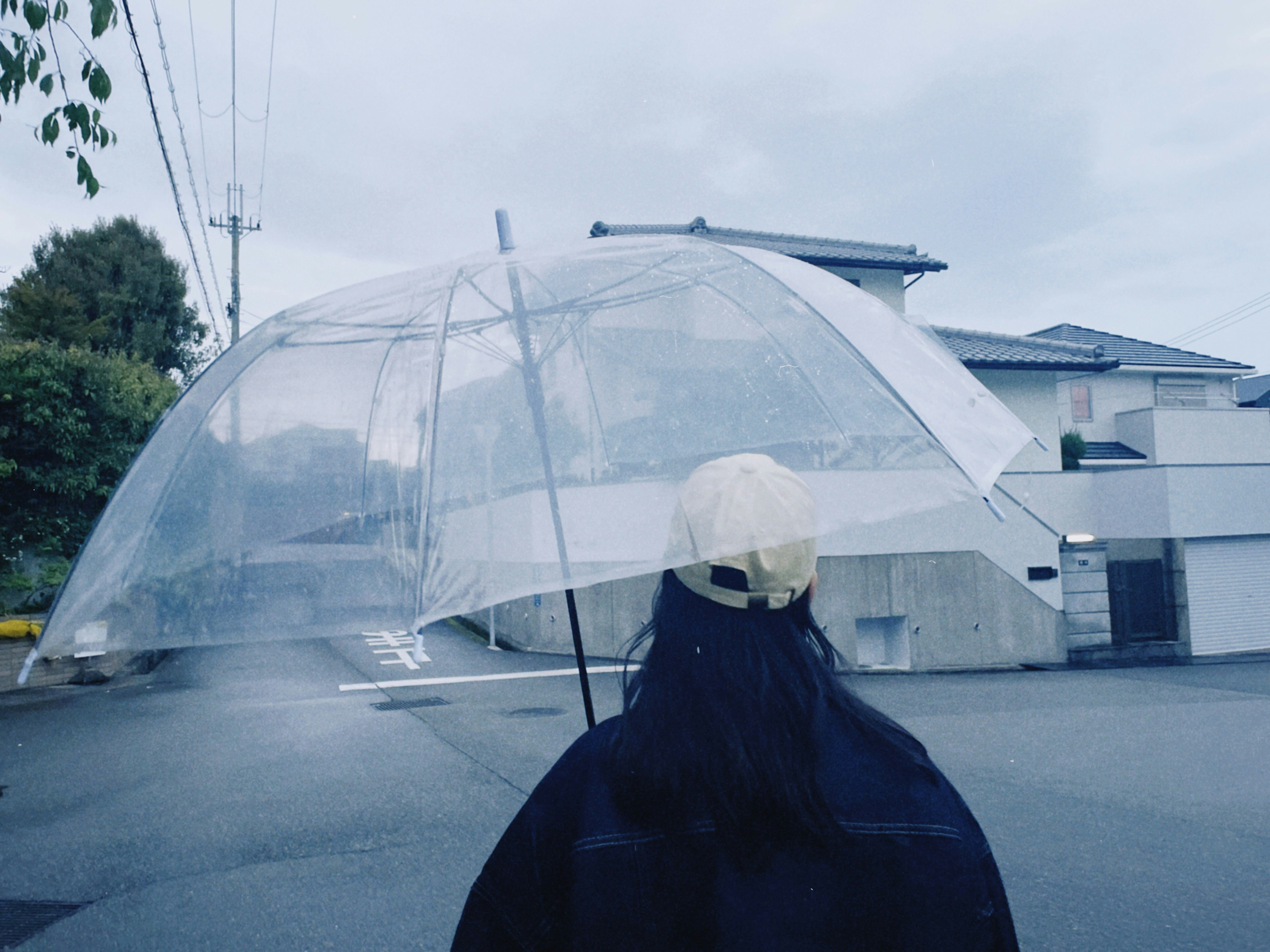 雨の日の路地で傘をさす人と透明なドームの建物