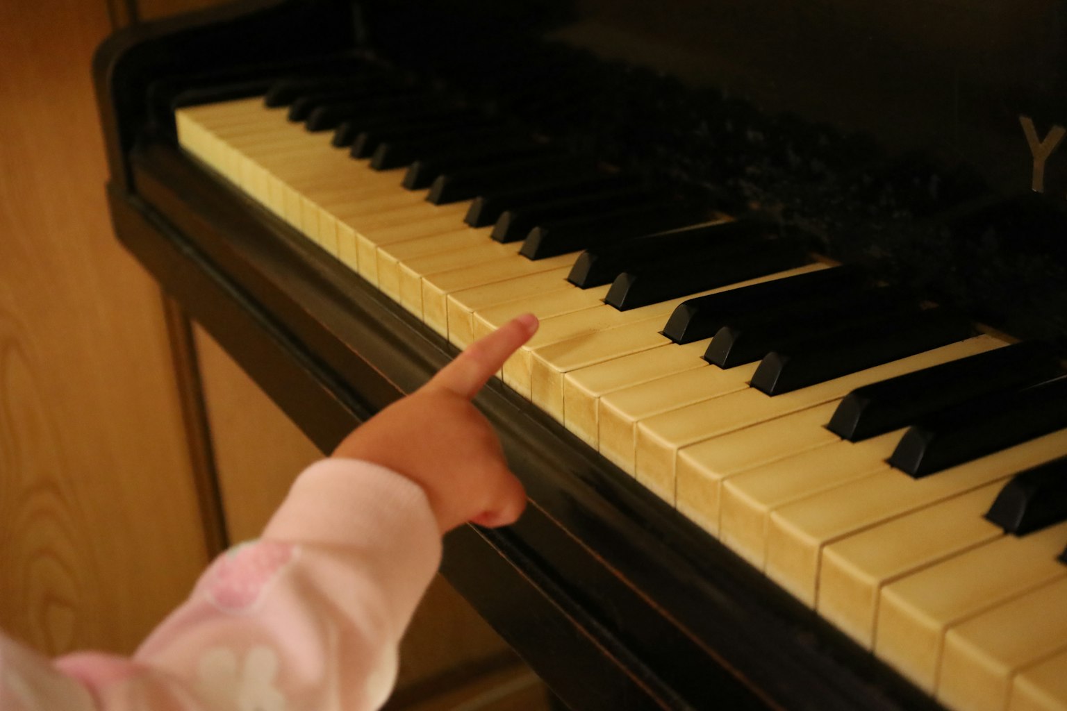 Tangan anak menunjuk ke tuts piano