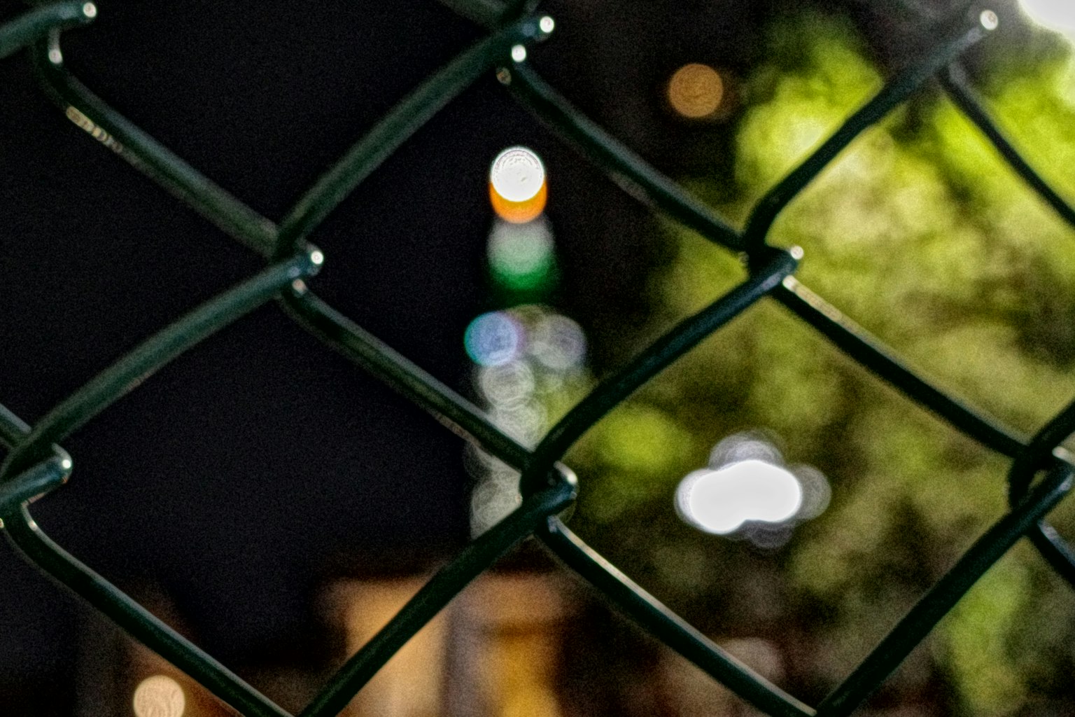 夜間圍籬透視的模糊燈光和綠色背景