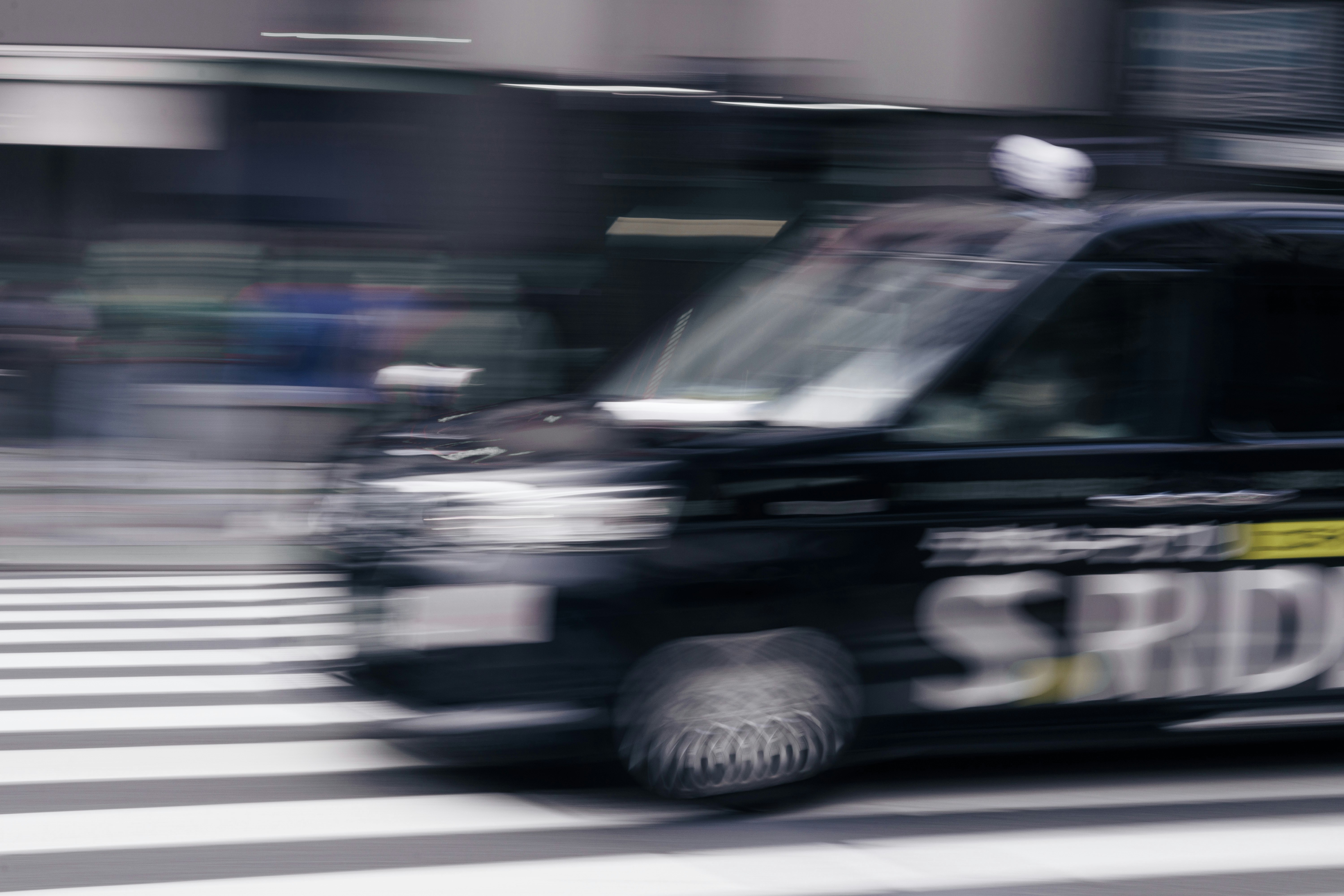 新宿の横断歩道を走る車とバスのある街並み