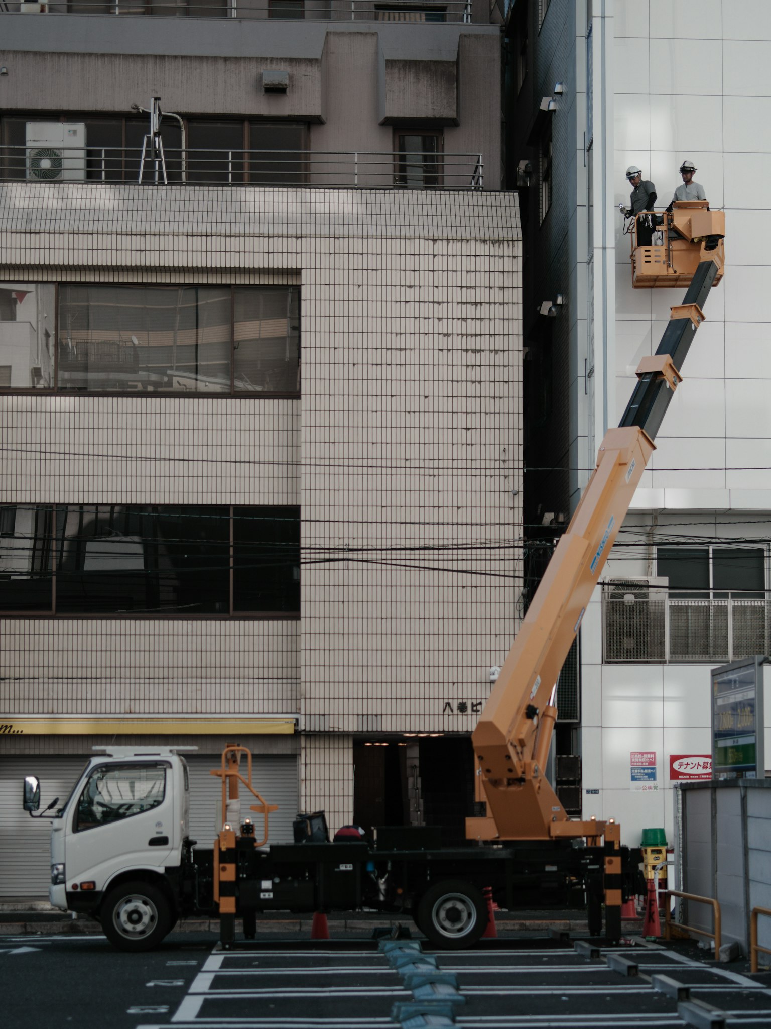 在建筑外立面上进行维护的起重机和工人