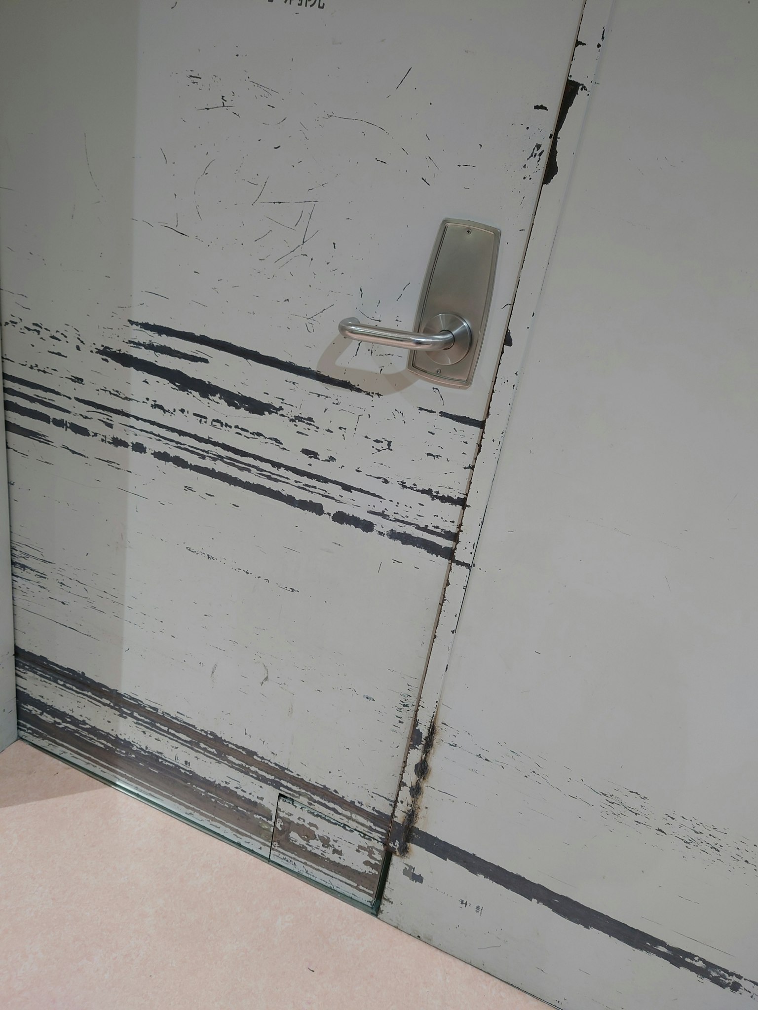 Primo piano di una vecchia porta metallica con graffi e vernice scrostata e una maniglia attaccata