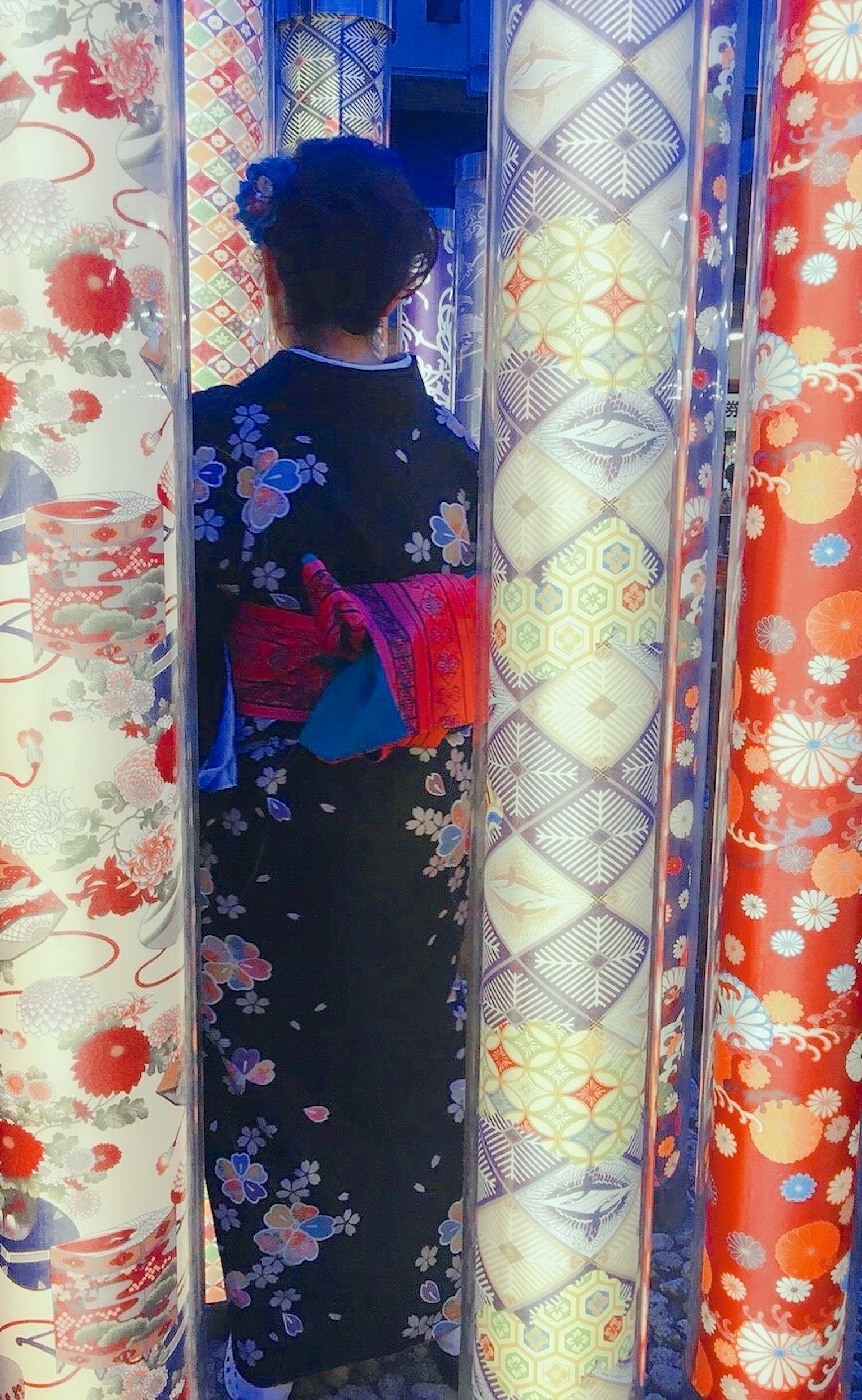 Người phụ nữ trong kimono đứng giữa những cuộn vải đầy màu sắc