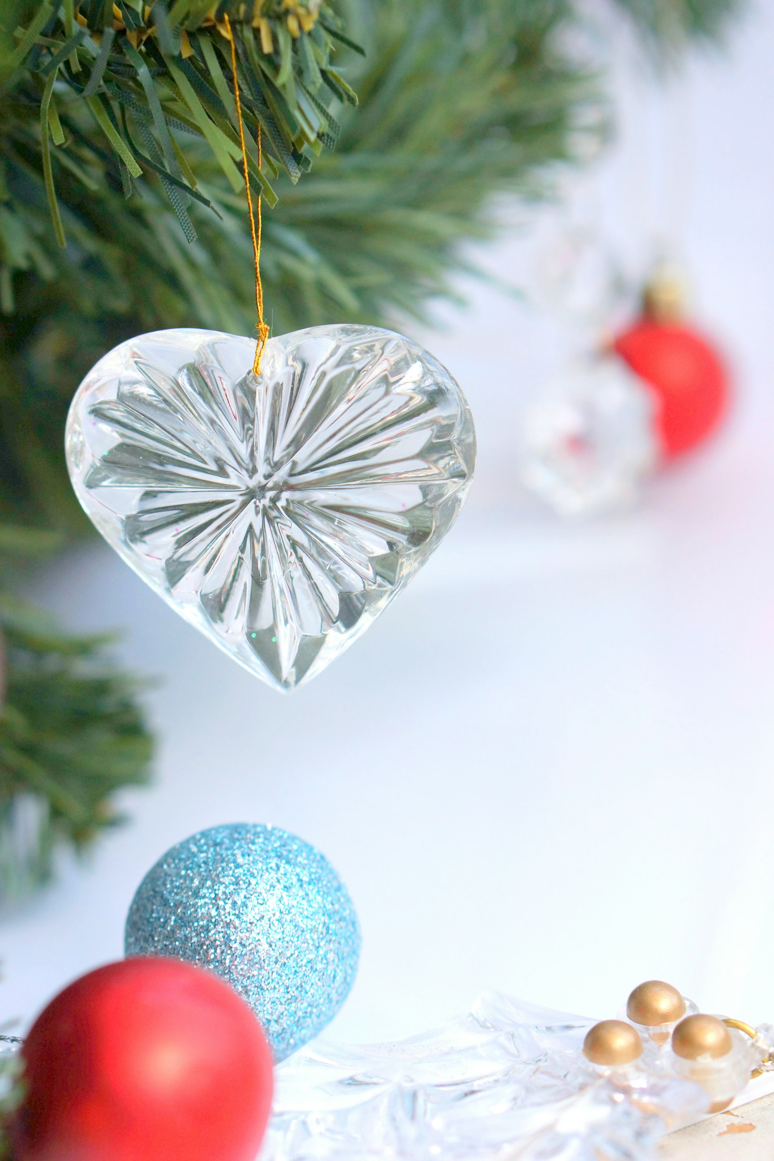 Đồ trang trí hình trái tim bằng thủy tinh treo trên cây thông Noel với các đồ trang trí nhiều màu sắc