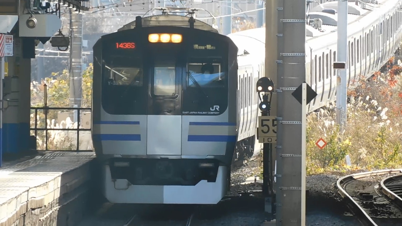 Vista frontale di un treno in stazione con un palo di segnalazione