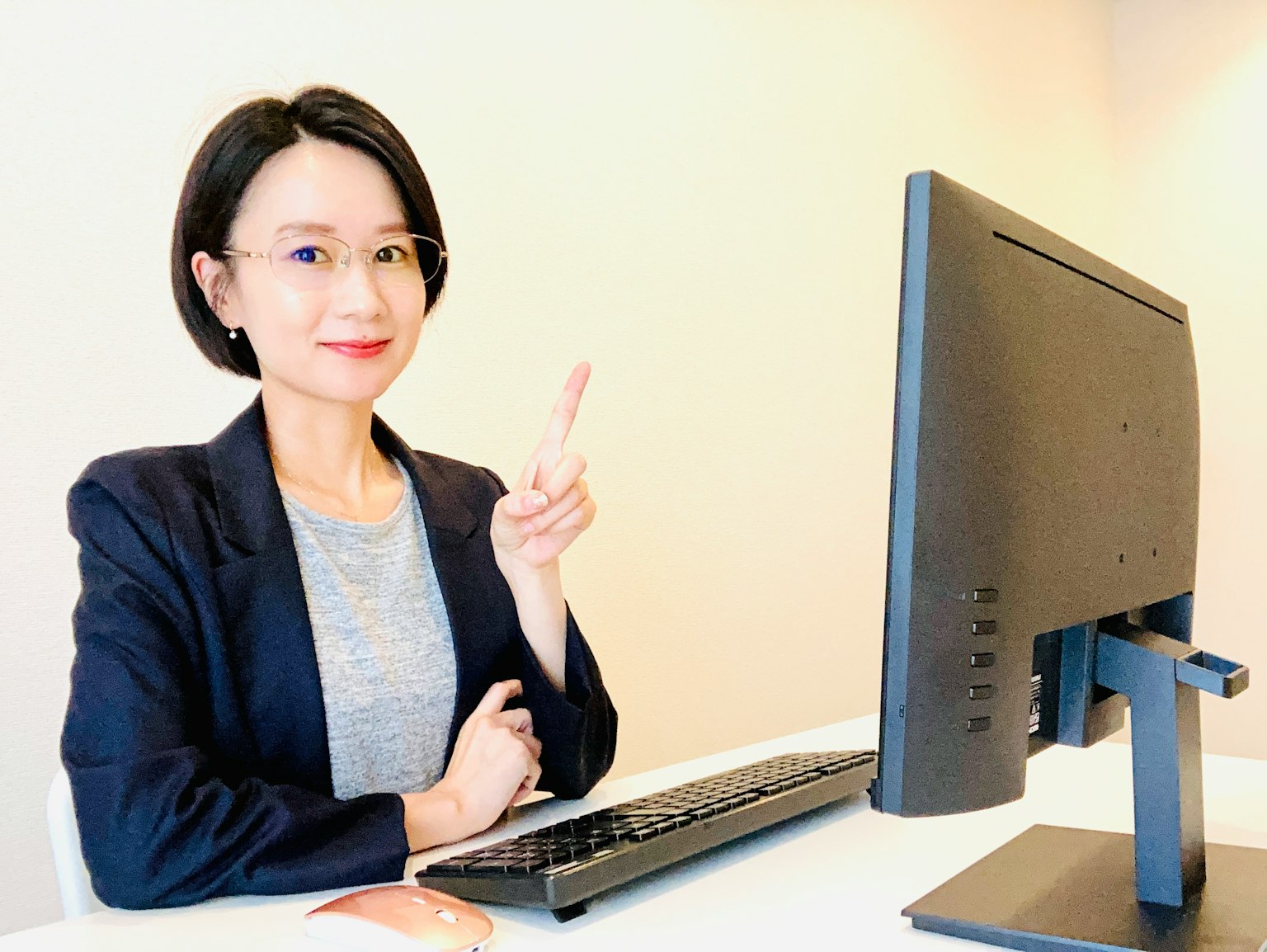 여성이 컴퓨터 앞에서 미소를 지으며 평화의 손가락을 하고 있다