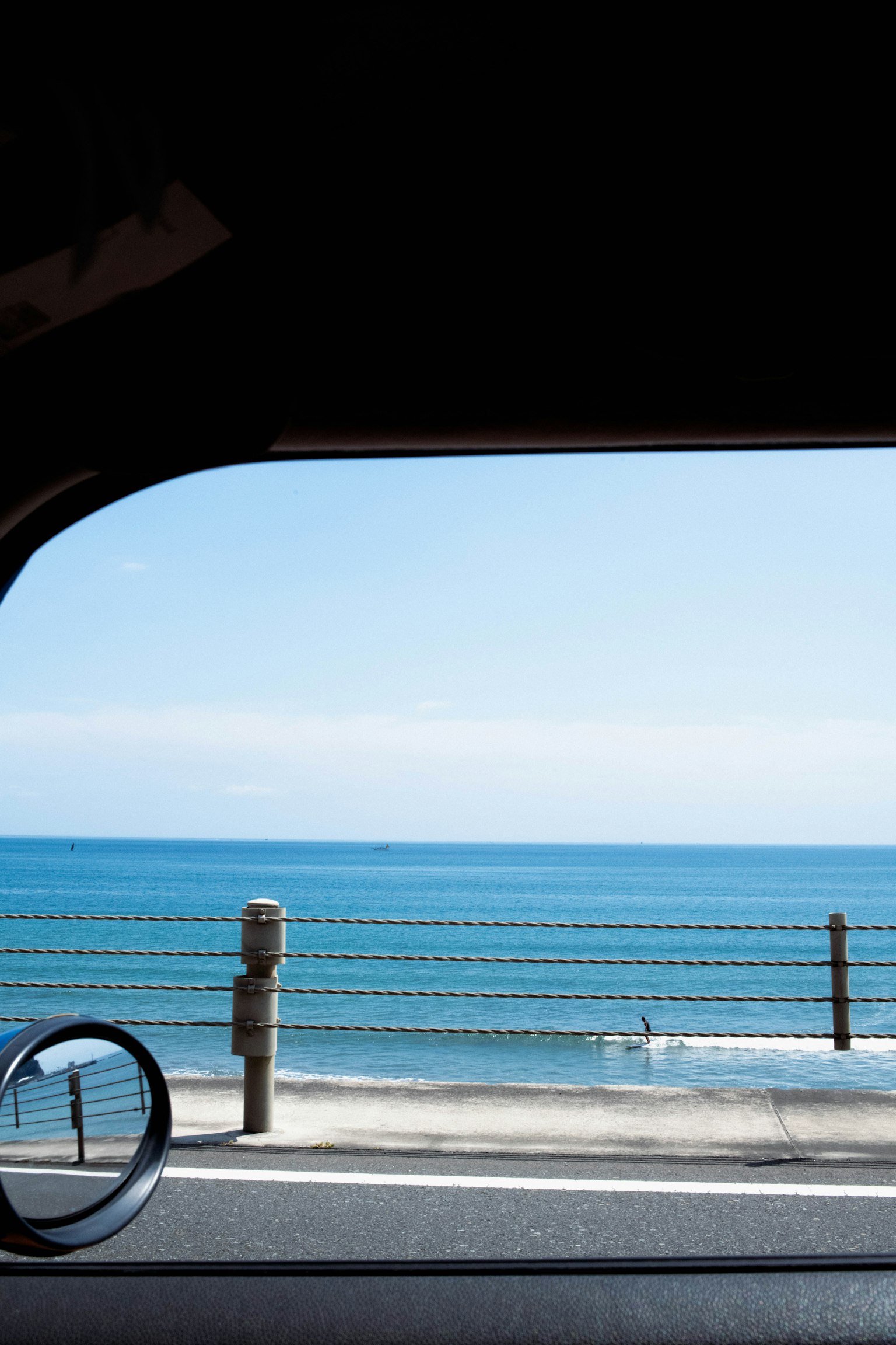 Pemandangan lautan dan langit biru dari jendela mobil