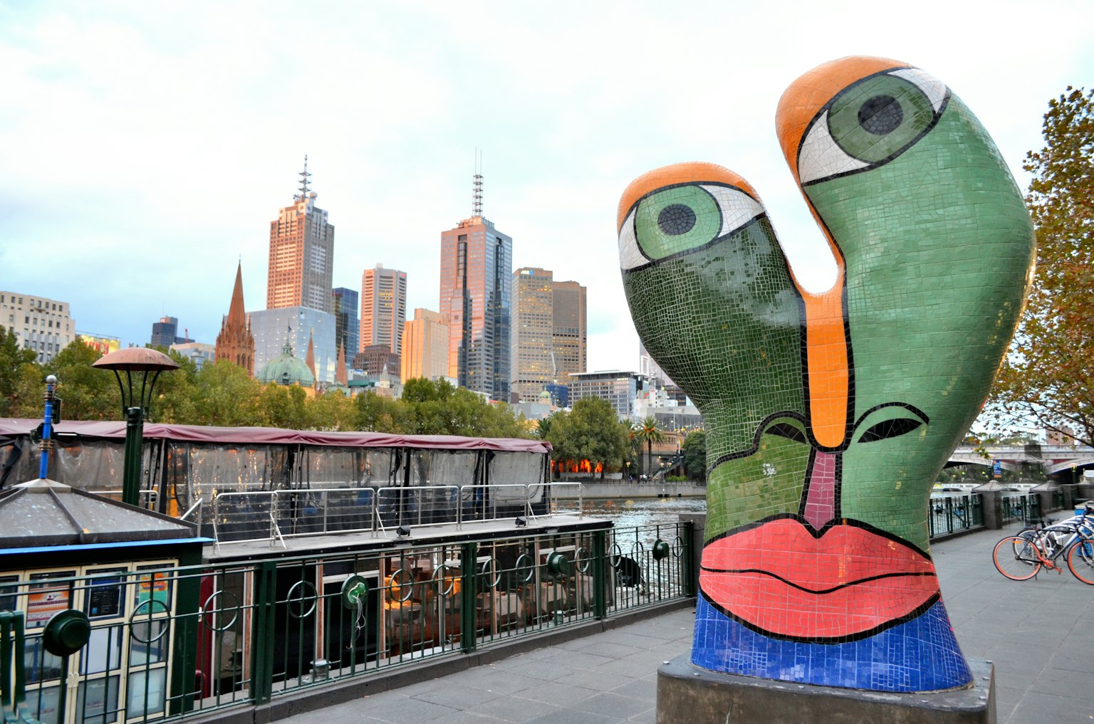 Colorful sculpture with face motifs in Melbourne cityscape background