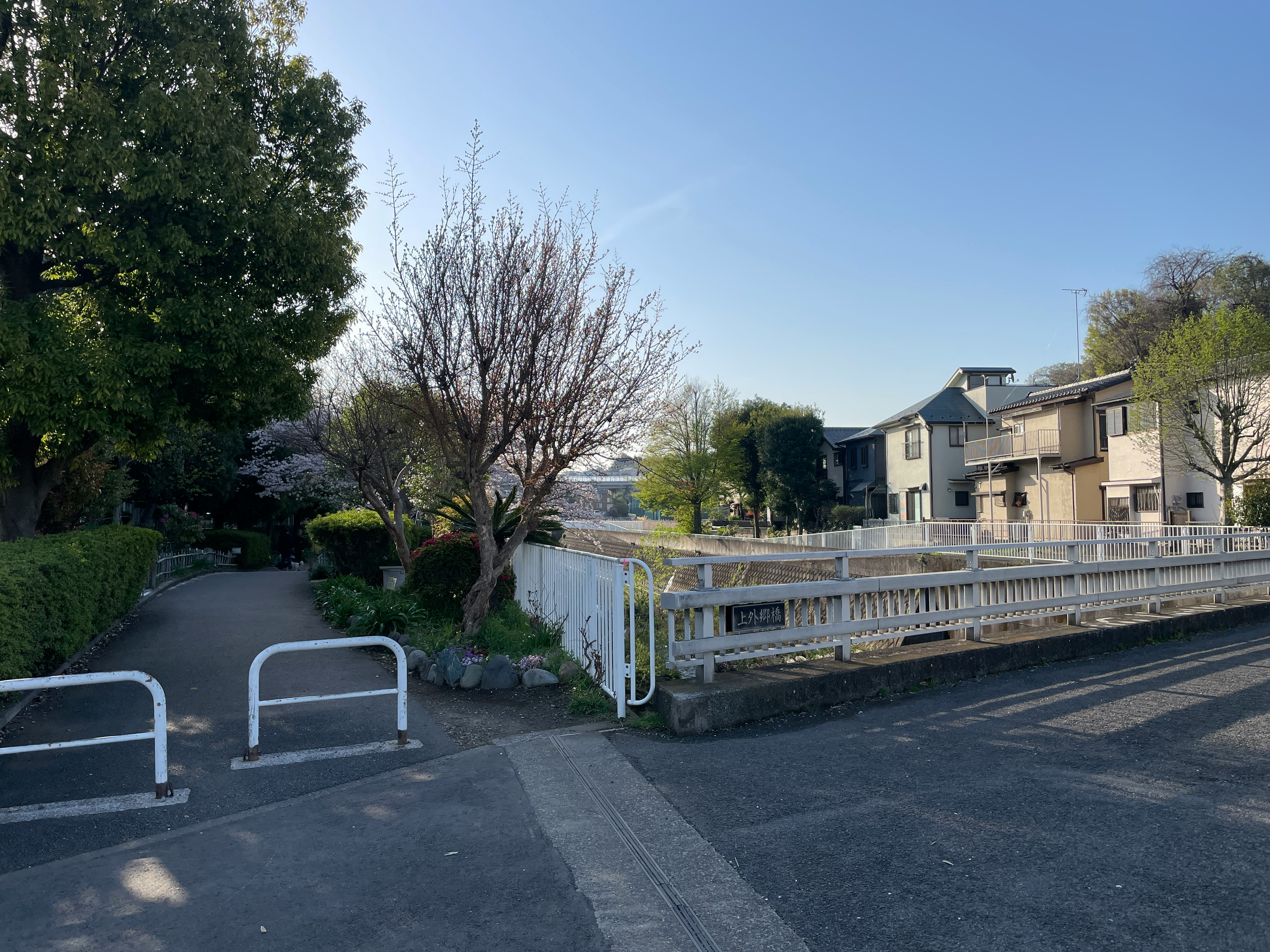 住宅街の歩道と白い手すりのある小さな橋
