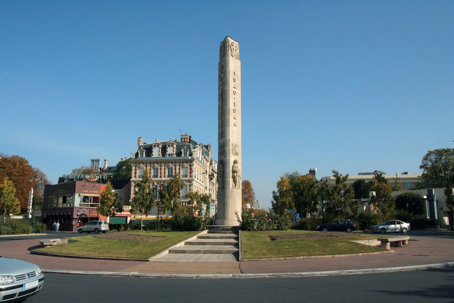 Alto monumento al centro di una rotonda con edifici circostanti