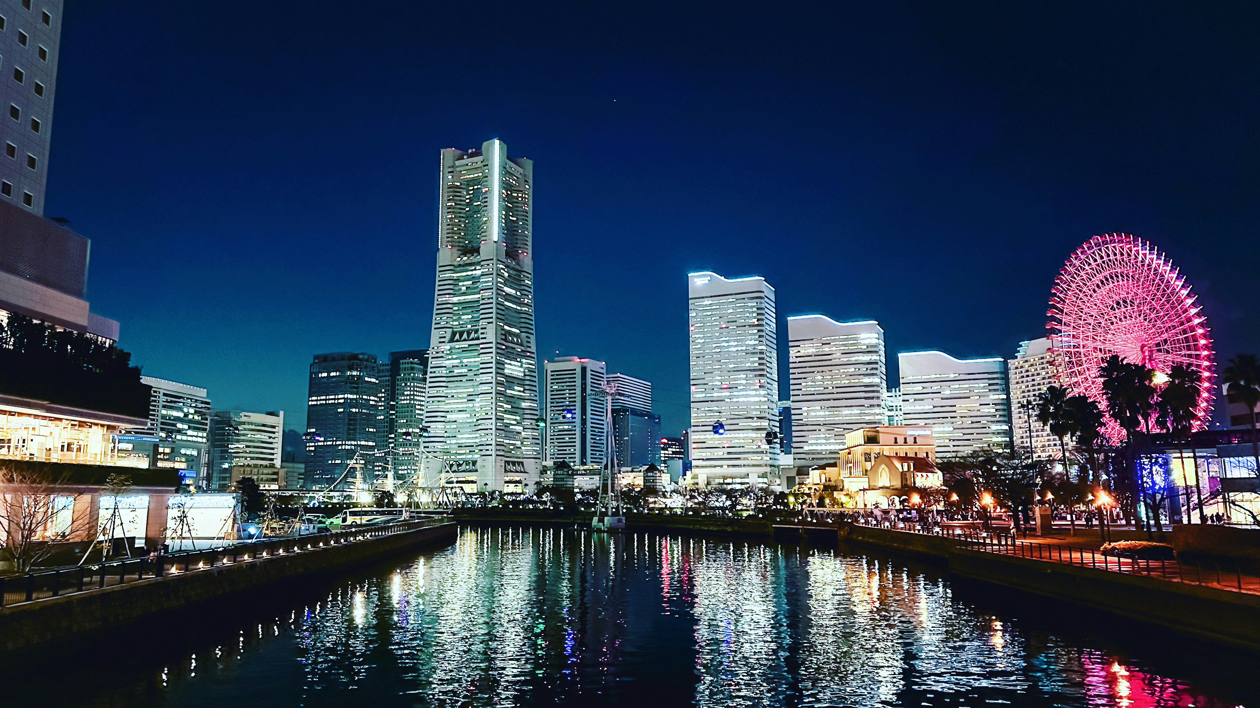 運河沿いの夜景と観覧車のある大都市のスカイライン