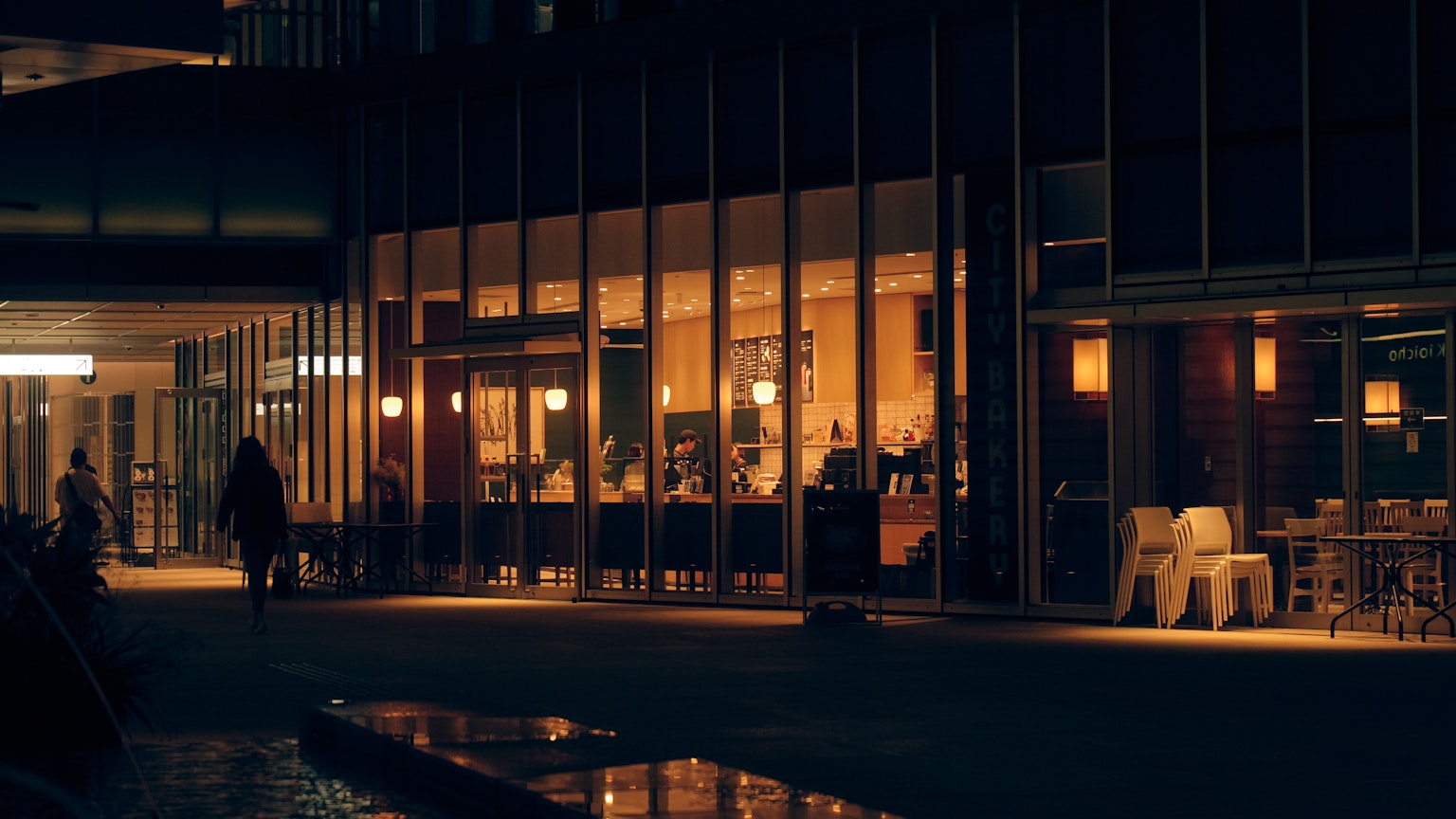 Exterior view of a cafe at night with people walking