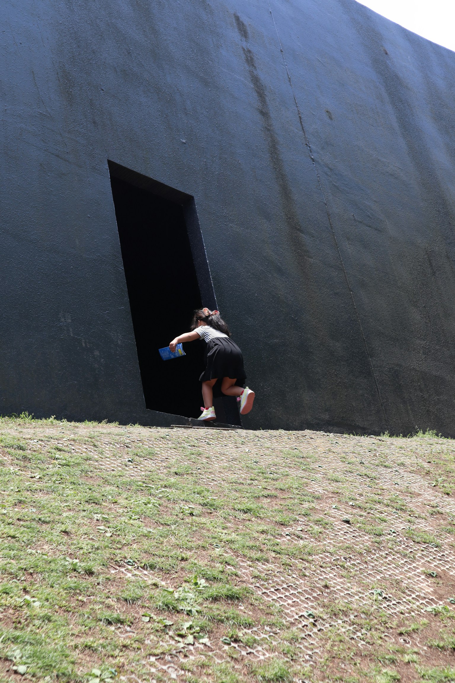 Enfant grimpant vers l'entrée d'un bâtiment noir