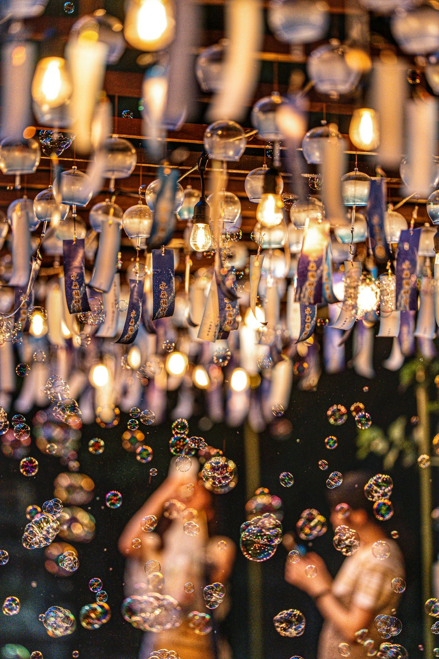 People enjoying amidst bubbles and lights with hanging lamps and wind chimes