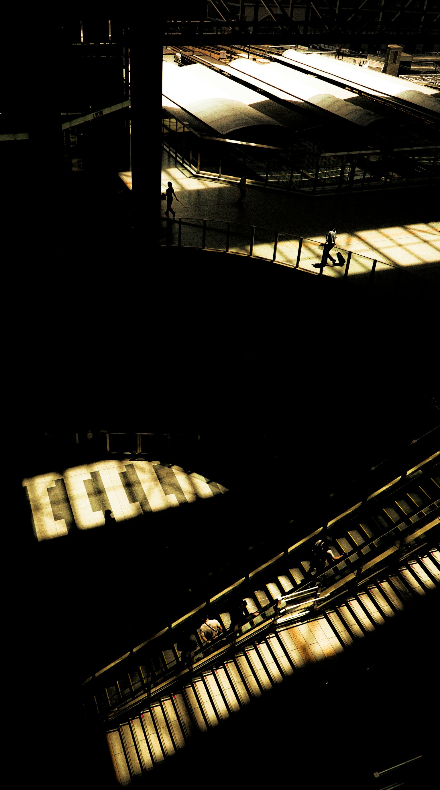Composition with bright light streaming into a dark space featuring people walking