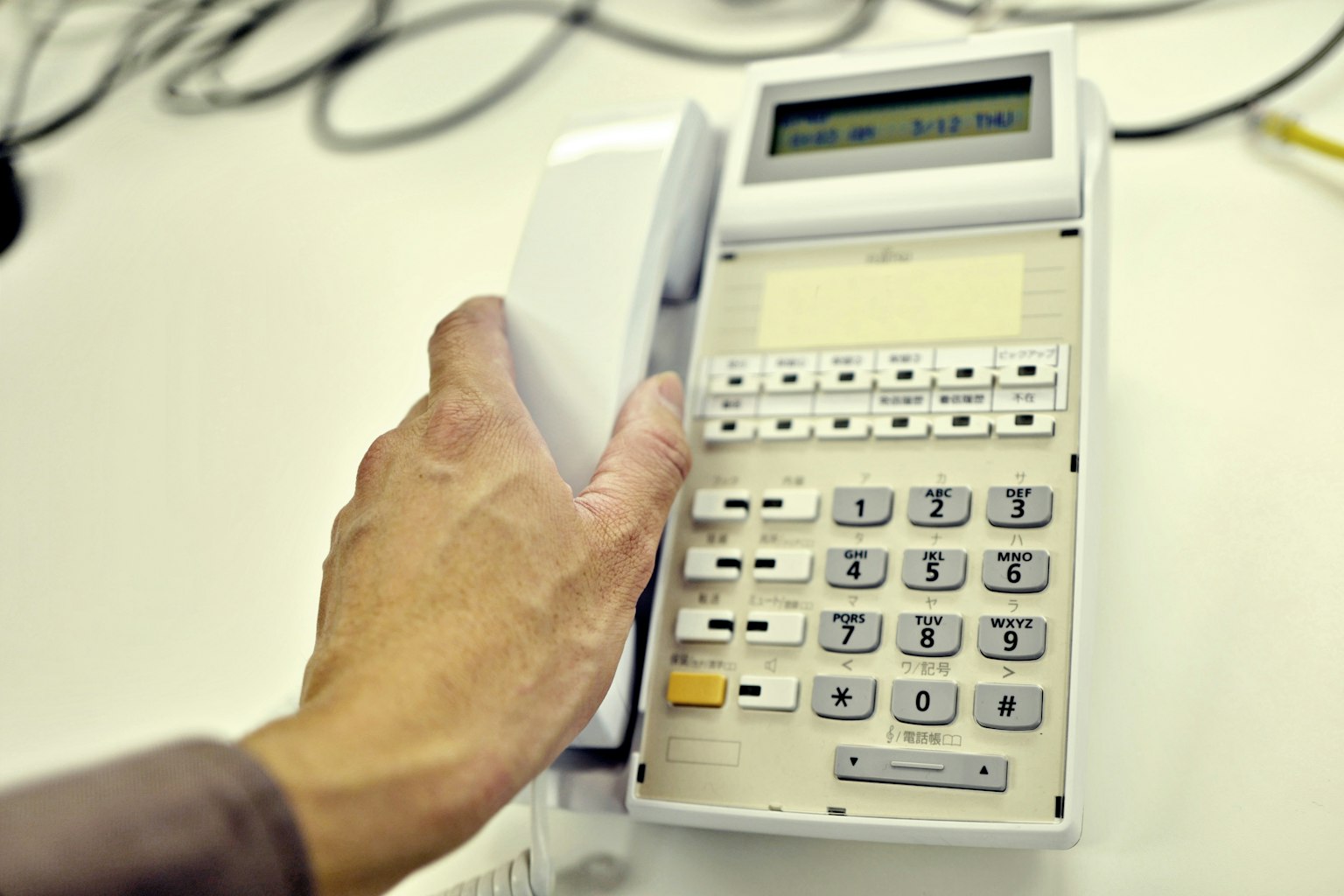 Primo piano di un telefono fisso bianco tenuto in mano