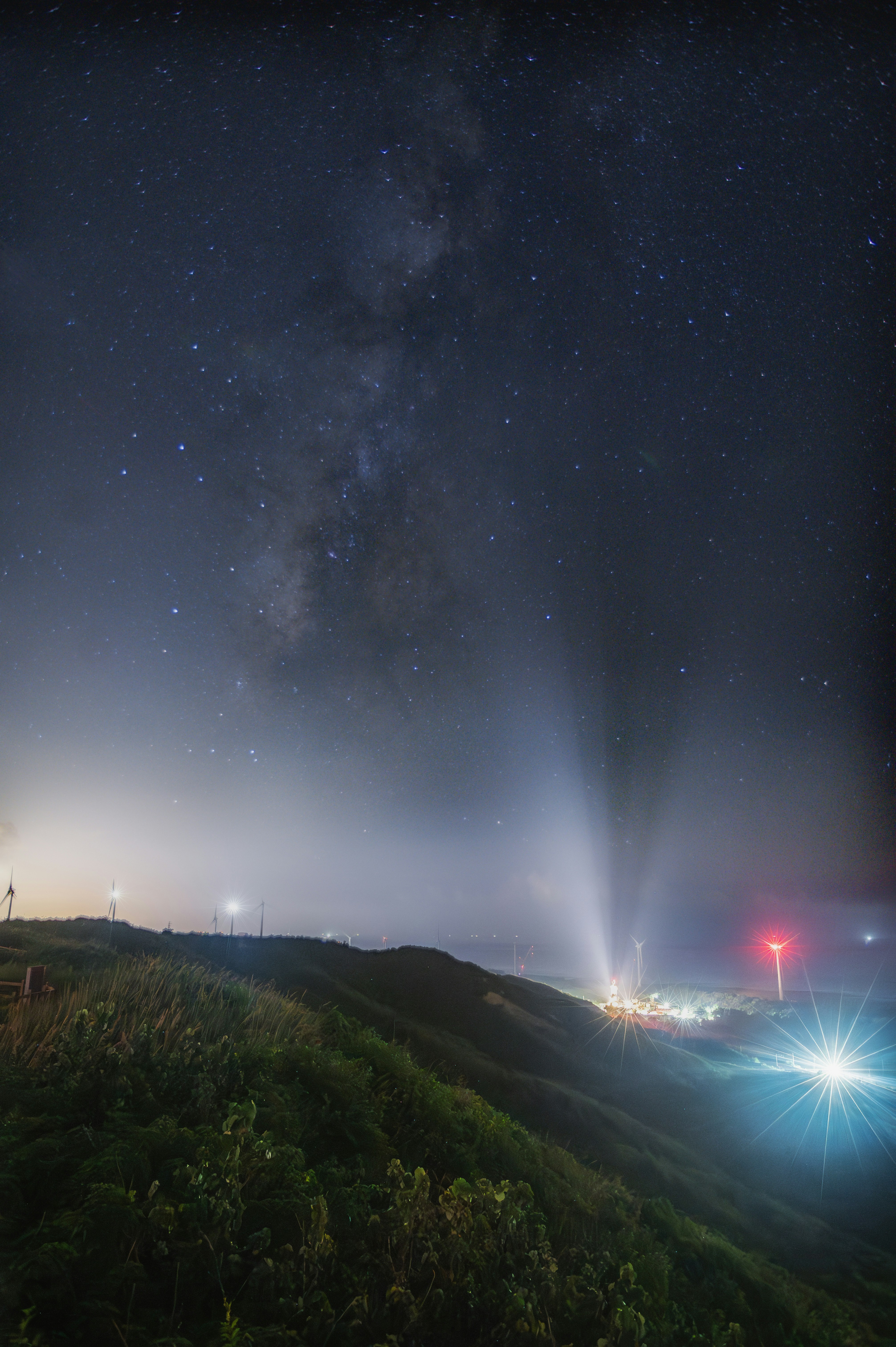 夜空の星と山稜に伸びる光の筋のある風景