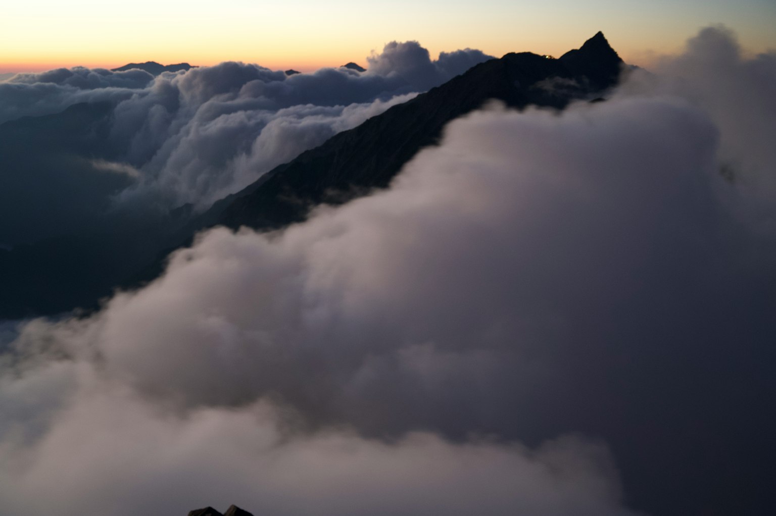 Siluet gunung yang tertutup awan dengan langit senja