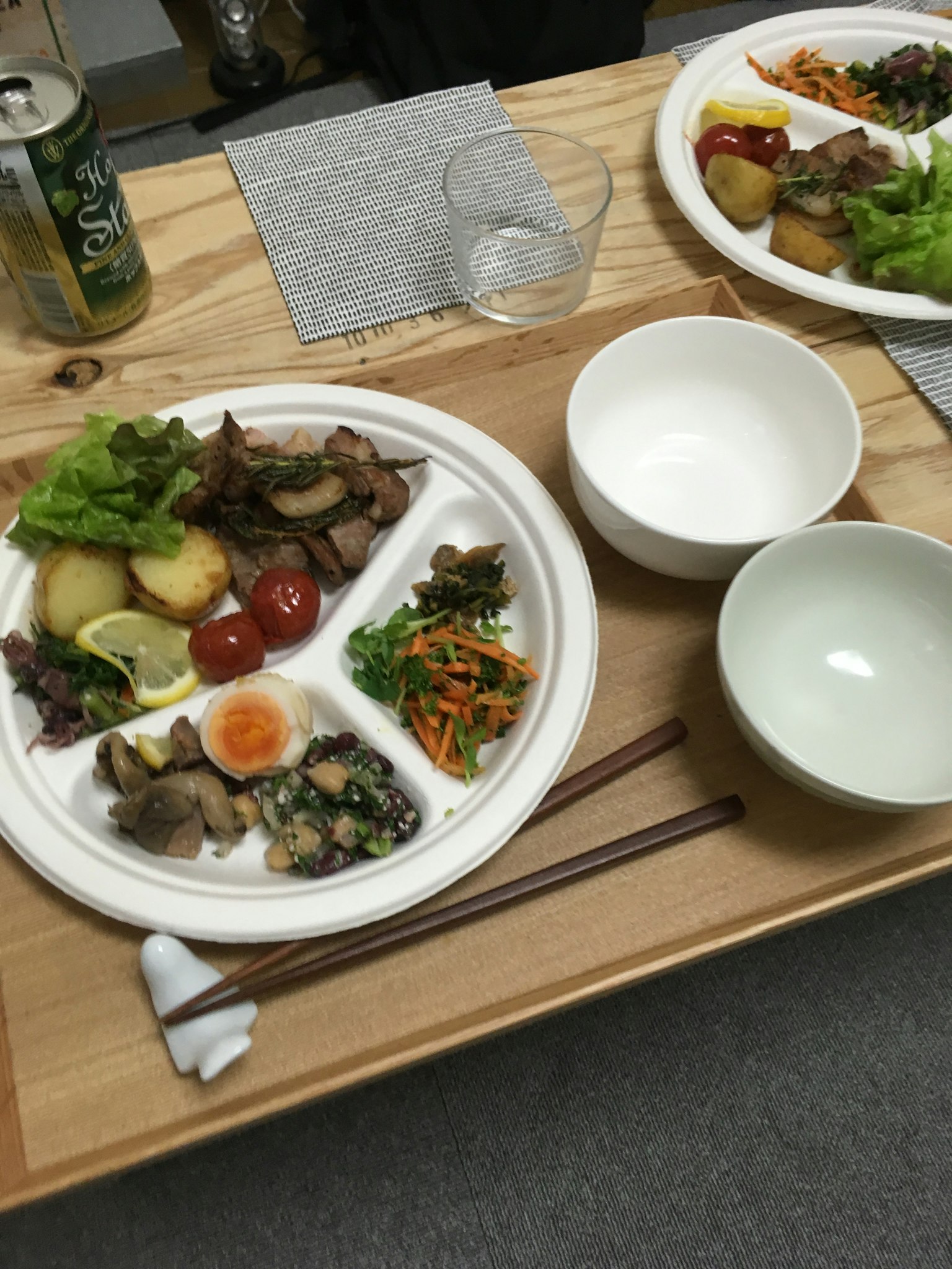 Plato servido en una mesa de madera con carne, verduras, huevo, ensalada y guarniciones