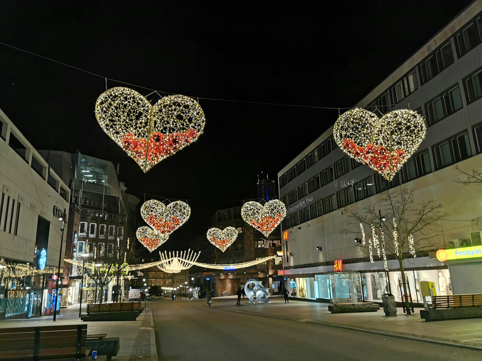 Una scena di strada di notte con luci a forma di cuore appese sopra