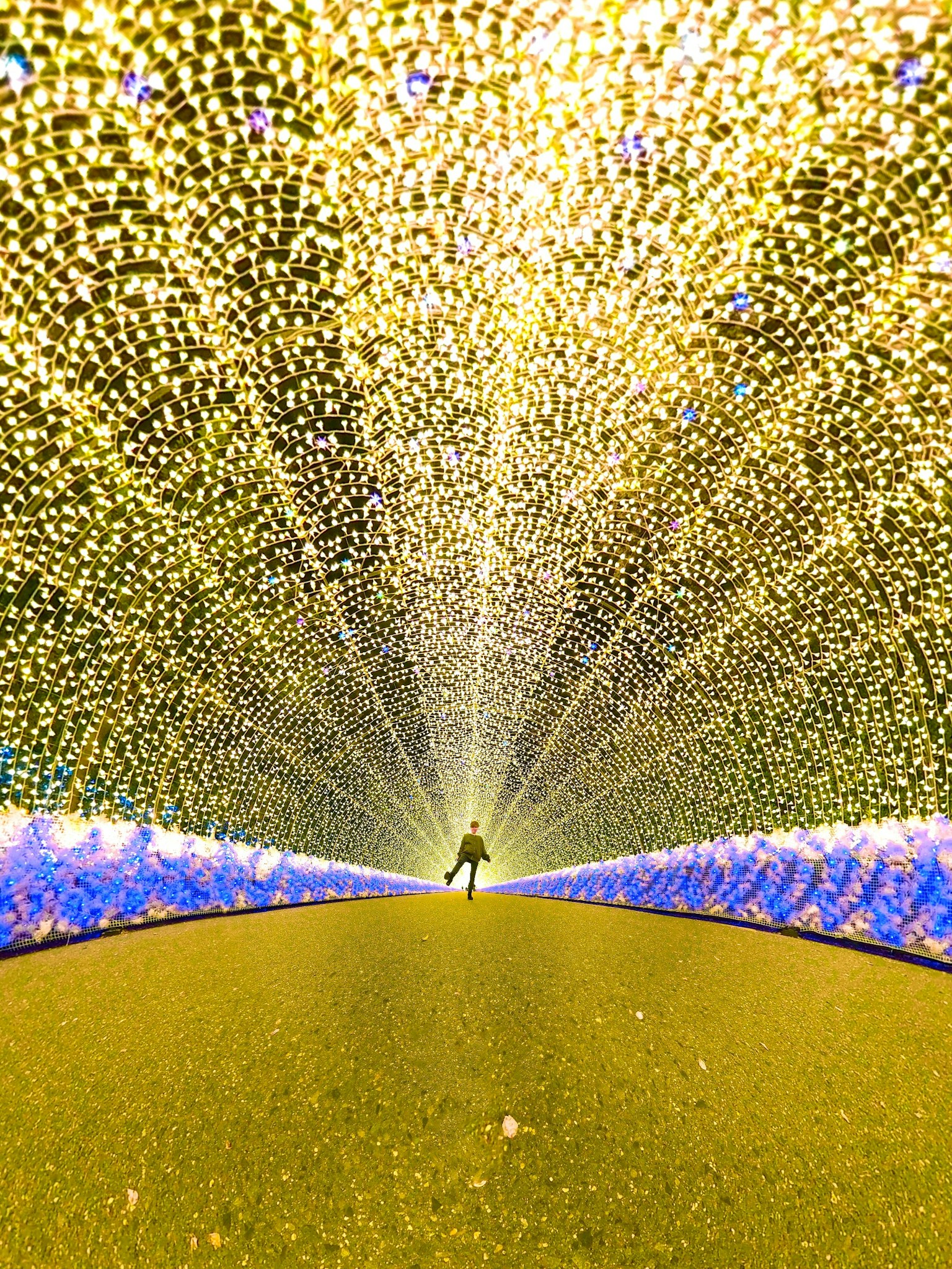 Une personne se tenant au centre d'une belle installation lumineuse dans un tunnel de lumières